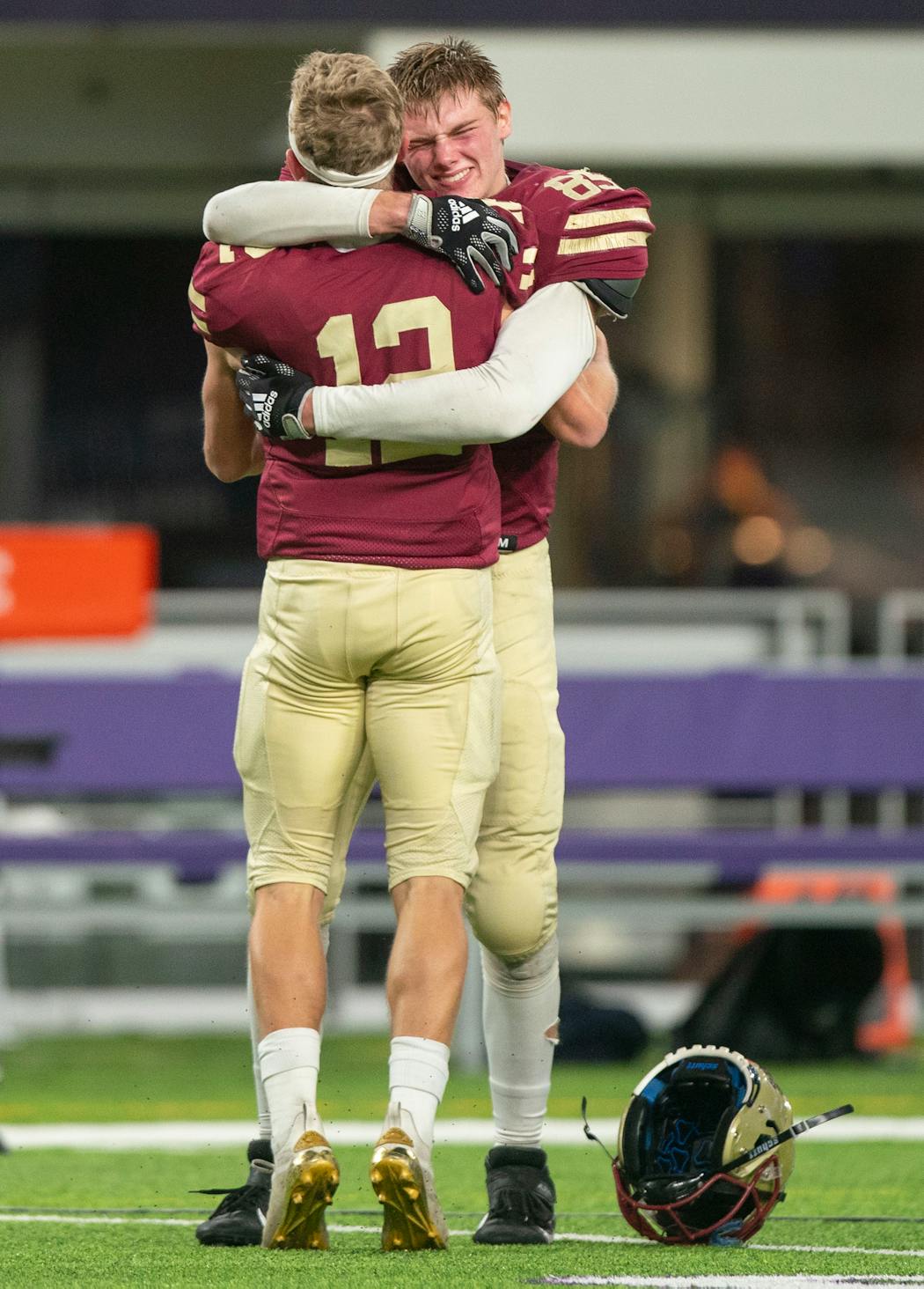 Lakeville South quarterback Camden Dean (12) and tight end Zach Juckel embraced after the Cougars secured the 2021 Class 6A title. Each is on to college football, adding to the challenge faced in 2022 by coach Ben Burk.