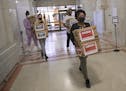 Corenia Smith, campaign manager with Vote Yes 4 Minneapolis, led a group carrying boxes of signed petitions into City Hall.