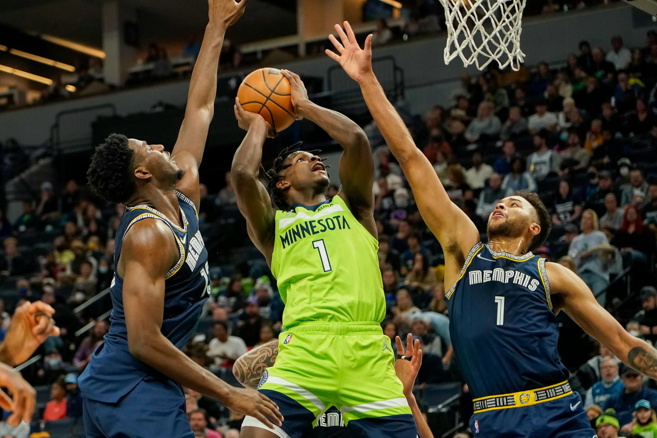 Minnesota Timberwolves guard Anthony Edwards, center, goes up to shoot between Memphis Grizzlies forward Kyle Anderson, right, and forward Jaren Jackson Jr. during the second half of an NBA basketball game Saturday, Nov. 20, 2021, in Minneapolis. (AP Photo/Craig Lassig)