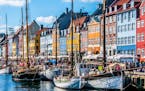 iStockphoto.com Copenhagen, Denmark - November 30, 2014: Crowds of people on the picturesque waterfront of Nyhavn. Coloured historic houses and blue w