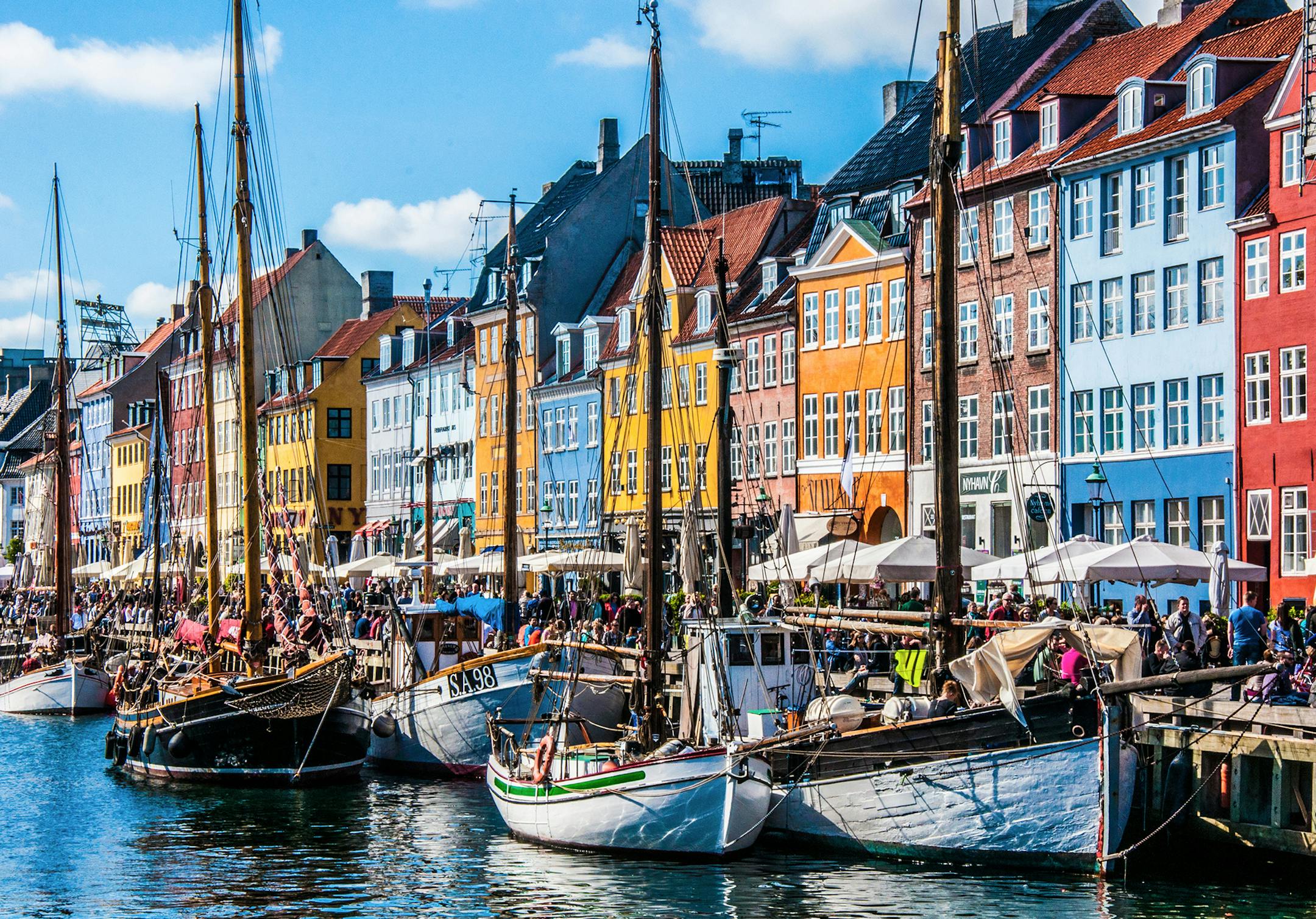 iStockphoto.com Copenhagen, Denmark - November 30, 2014: Crowds of people on the picturesque waterfront of Nyhavn. Coloured historic houses and blue water of the harbour canal.