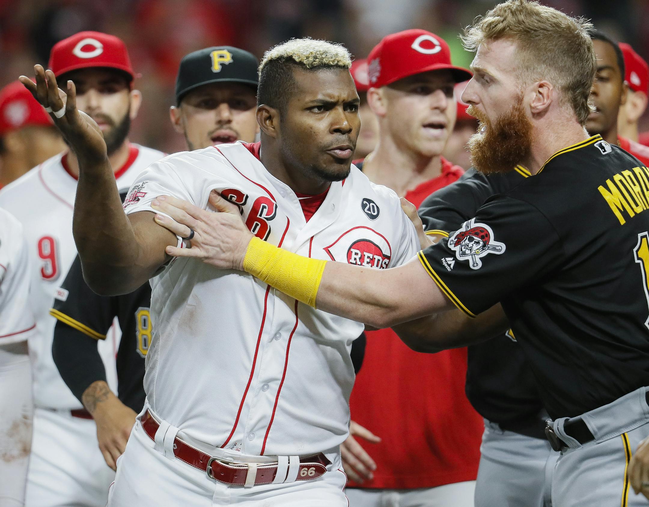 Cincinnati Reds' Yasiel Puig (66) is restrains by Pittsburgh Pirates third baseman Colin Moran (19) during the ninth inning of a baseball game Tuesday, July 30, 2019, in Cincinnati. (AP Photo/John Minchillo)
