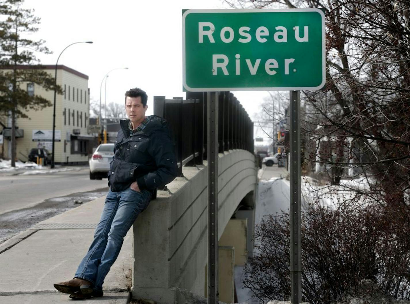 ADVANCE FOR USE MONDAY, MARCH 24, 2014 AT 3 A.M. AND THEREAFTER - Bob Brellenthin of Pahlen Realty stands at a bridge crossing the Roseau River in Roseau, Minn. on Thursday, March 20, 2014. He knows first hand the effect the new, higher national flood insurance premiums have had on his business and the difficulty his customers have had selling their homes because of the changes in the National Flood Insurance Program.