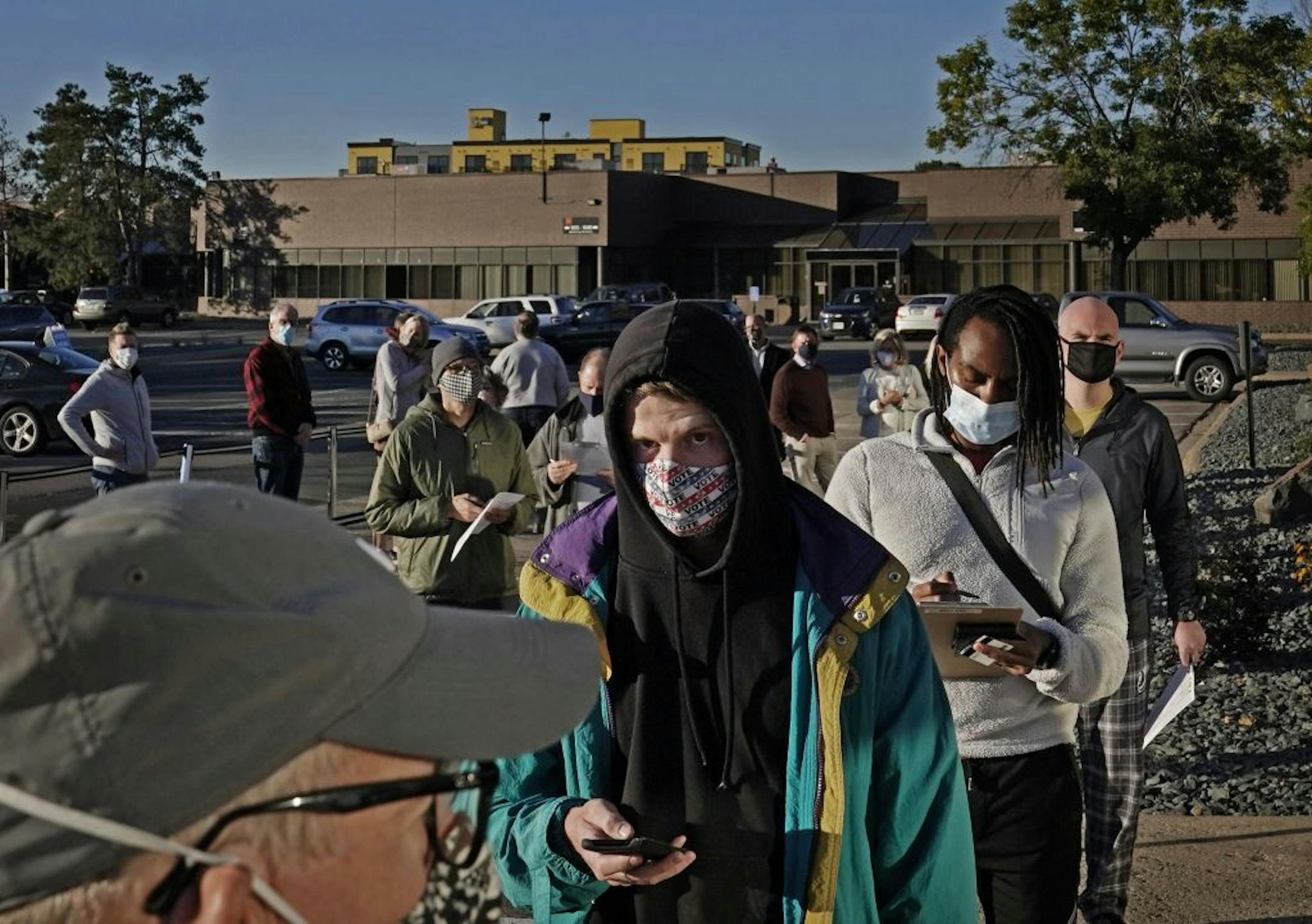 Jack O'Rourke of Minneapolis, whose mother made him a custom mask urging people to vote, joined other voters during early voting at Minneapolis Elections and Voter Services Friday in Minneapolis. O'Rourke said he is looking "at the state of the country," in the pandemic and believes the U.S. is far worse off than other developed nations and that is what he said he will base his vote on.