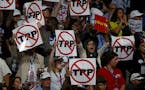 California delegates hold up signs against the Trans-Pacific Partnership on the first night of the Democratic National Convention on Monday, July 25, 