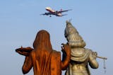 Statue of Hindu Gods Radha, left, and Krishna stand in the foreground as a Kingfisher Airlines flight approaches the Indira Gandhi International airport in New Delhi, India, Friday, Nov. 11, 2011. Kingfisher, which is partly owned by brewery tycoon Vijay Mallya, has canceled more than 120 flights this week as pilots and crew called in sick after their October salaries were delayed.