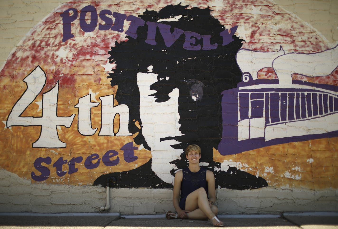 Katelin Krieg, who teaches a class on &#x201c;The Literary Bob Dylan,&#x201d; posed by the Dinkytown mural of Dylan and his song title words.