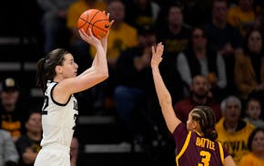 Iowa guard Caitlin Clark put up a shot over Gophers guard Amaya Battle during the first half Saturday in Iowa City.