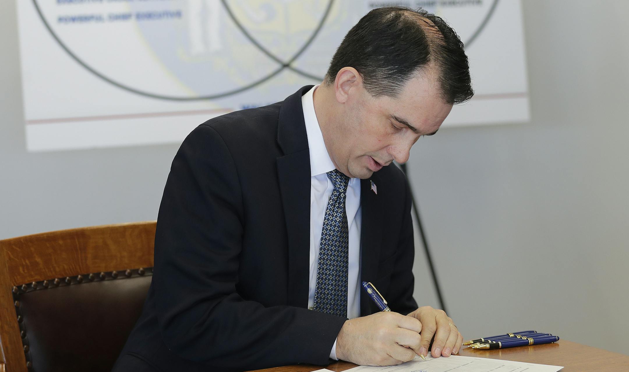 Gov. Scott Walker signs three pieces of legislation during a news conference Friday, Dec. 14, 2018 in Green Bay, Wis. Walker signed a sweeping package of Republican-written legislation Friday that restricts early voting and weakens the incoming Democratic governor and attorney general, brushing aside complaints that he is enabling a brazen power grab and ignoring the will of voters. (Haley BeMiller/The Post-Crescent via AP)