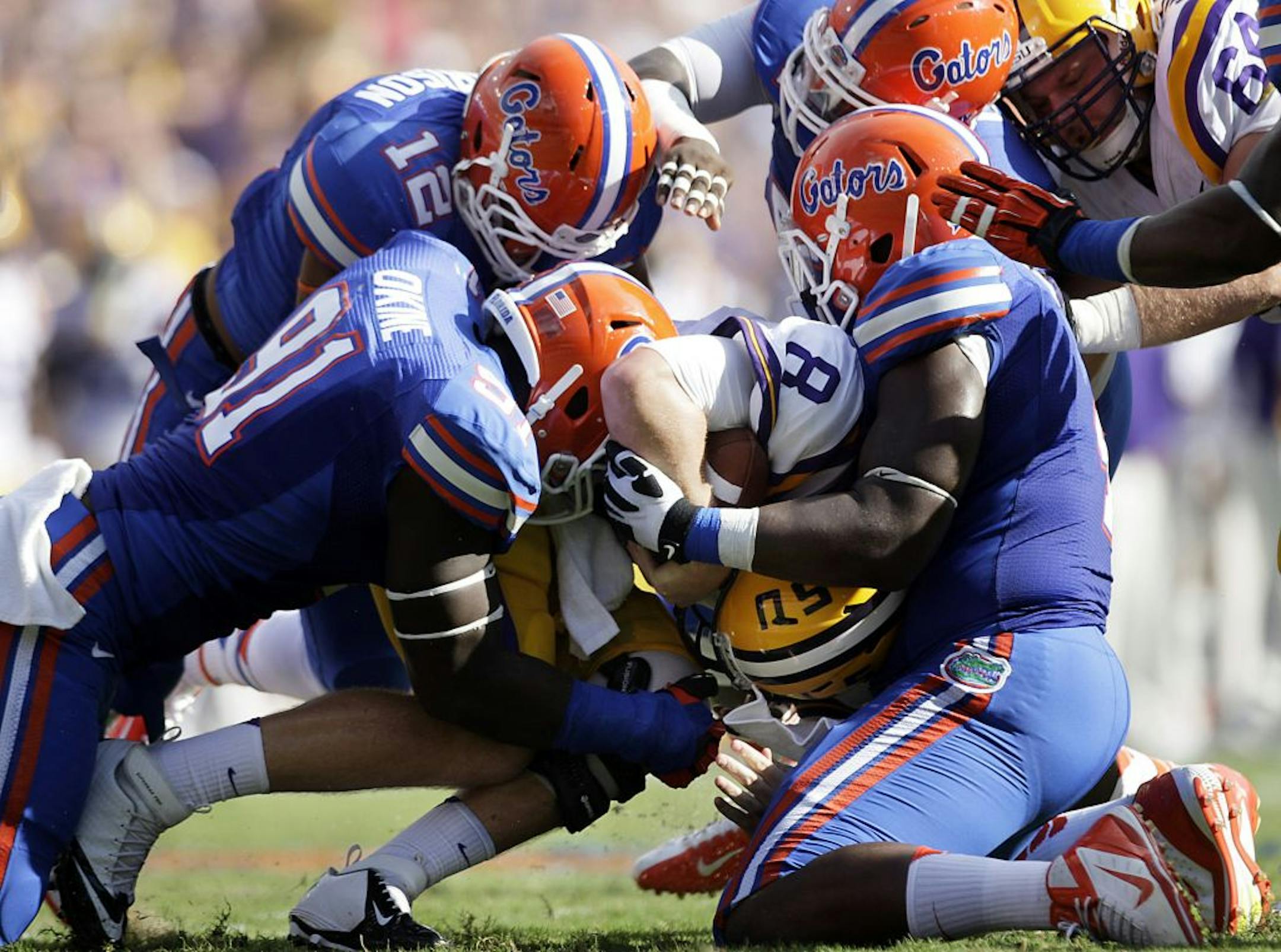 Florida Gators linebacker Antonio Morrison (12), defensive lineman Earl Okine (91) and defensive lineman Damien Jacobs (4) wrap up LSU Tigers quarterback Zach Mettenberger (8) behind the line of scrimmage during the second quarter at Ben Hill Griffin Stadium in Gainesville, Florida, Saturday, October 6, 2012. Florida defeated LSU, 14-6.