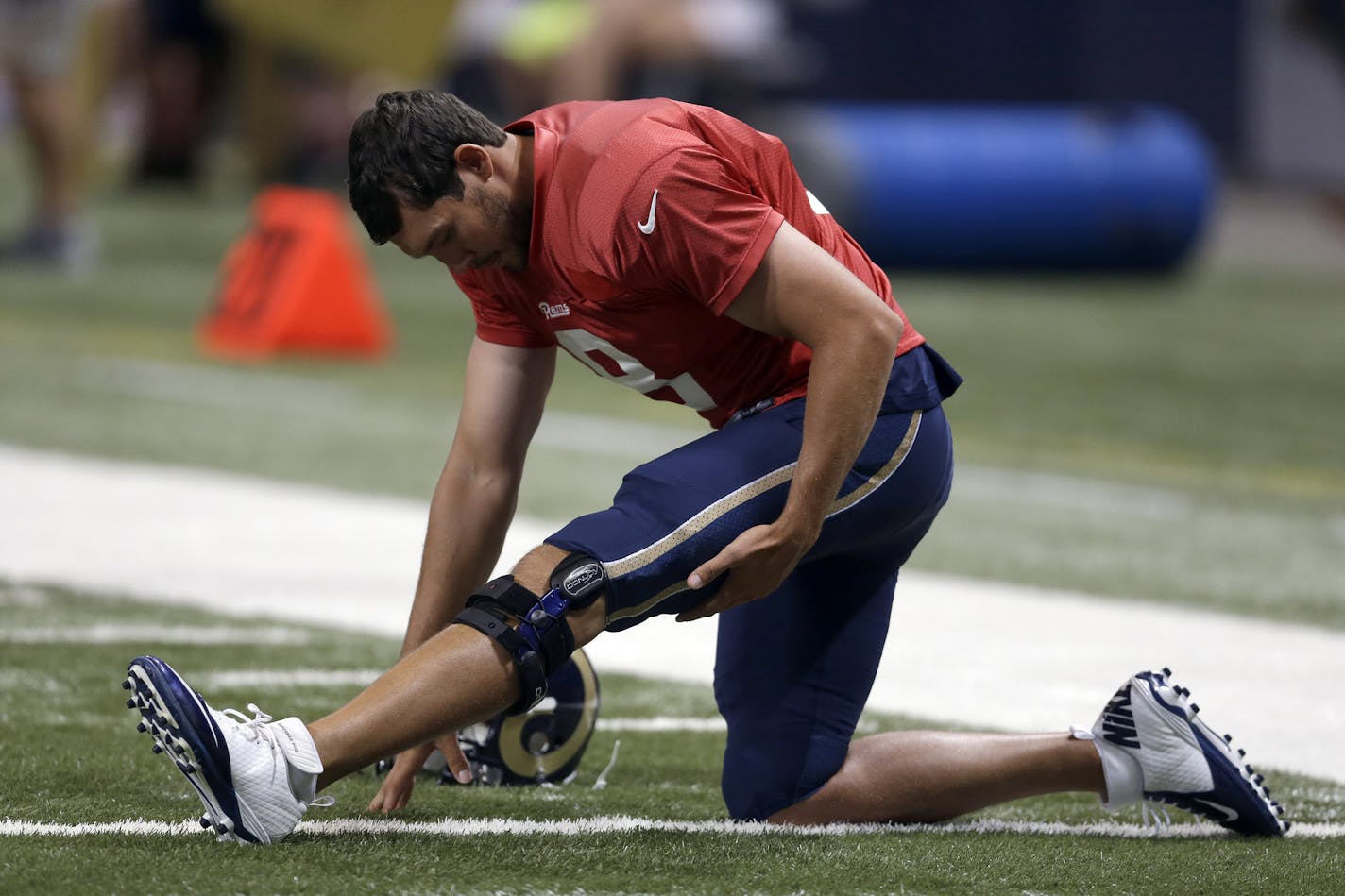 St. Louis Rams quarterback Sam Bradford wears a knee brace as he stretches at the start of practice during NFL football training camp at Edward Jones Dome Saturday, Aug. 2, 2014, in St. Louis. Bradford had surgery on his left knee following an injury that ended his season last year. (AP Photo/Jeff Roberson) ORG XMIT: MOJR