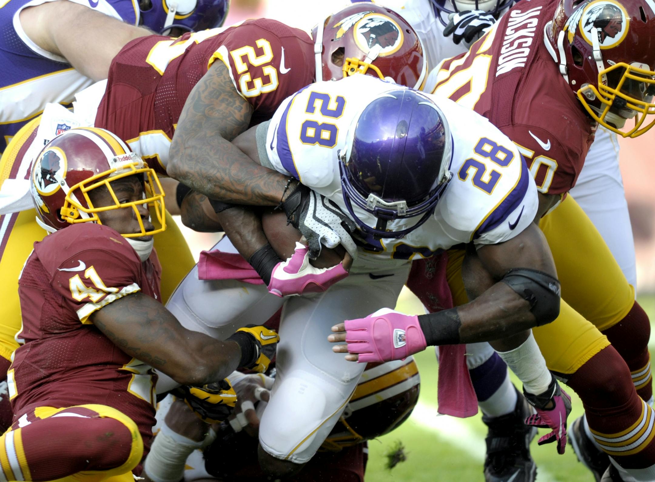Madieu Williams (41), DeAngelo Hall (23), and Rob Jackson (50), combine to bring down Vikings running back Adrian Peterson