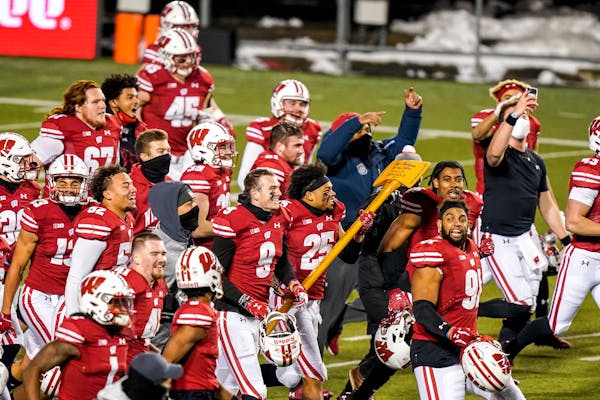 Wisconsin players celebrate with the Paul Bunyan Axe after they defeated Minnesota in overtime of an NCAA college football game Saturday, Dec. 19, 202