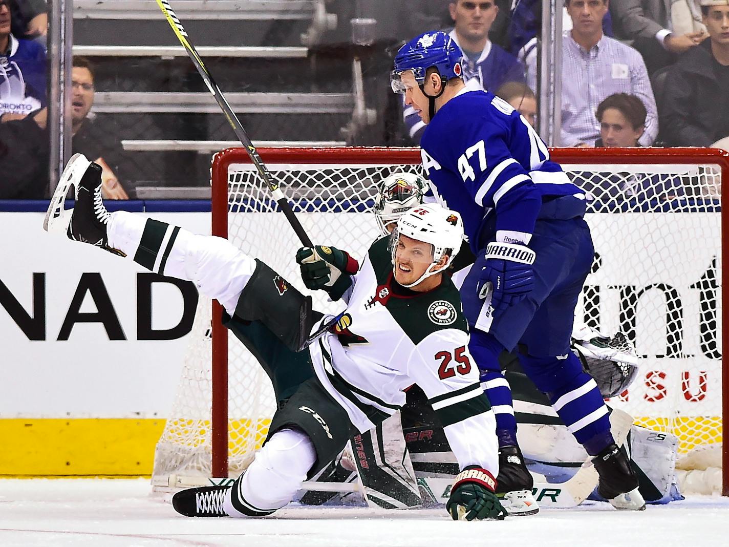 Toronto Maple Leafs center Leo Komarov (47) knocks down Minnesota Wild defenseman Jonas Brodin (25) in front of Wild goalie Devan Dubnyk during the first period of an NHL hockey game Wednesday, Nov. 8, 2017, in Toronto. (Frank Gunn/The Canadian Press via AP)