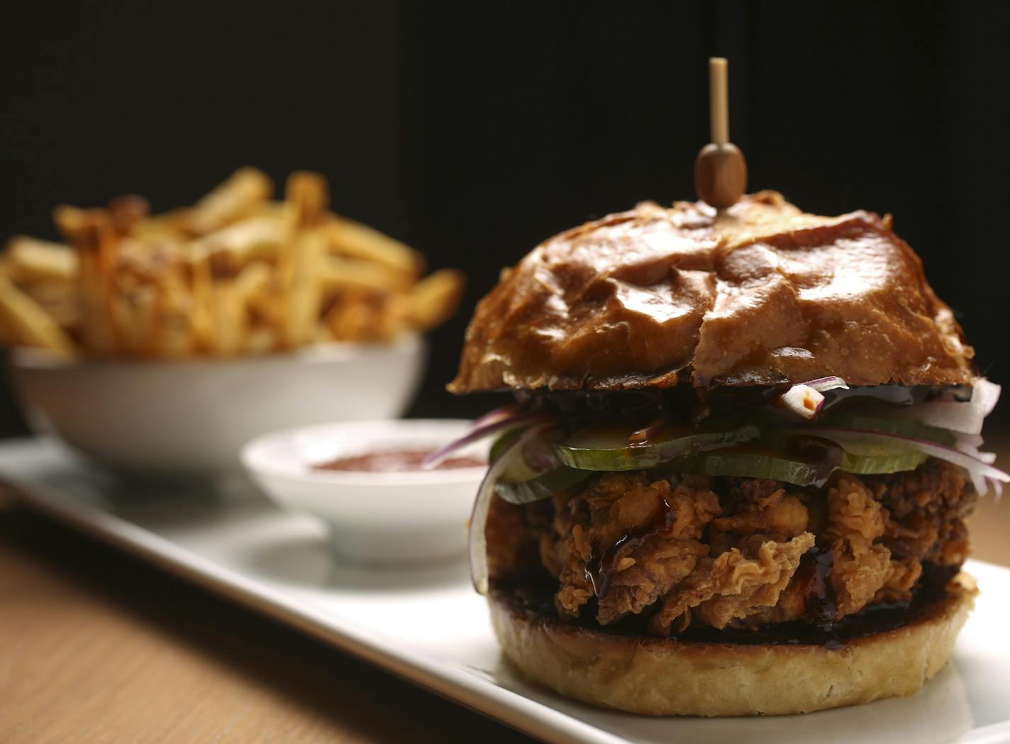 The Fried Chicken on a Pretzel Bun, with smoky barbeque, pickled cucumber and red onion.