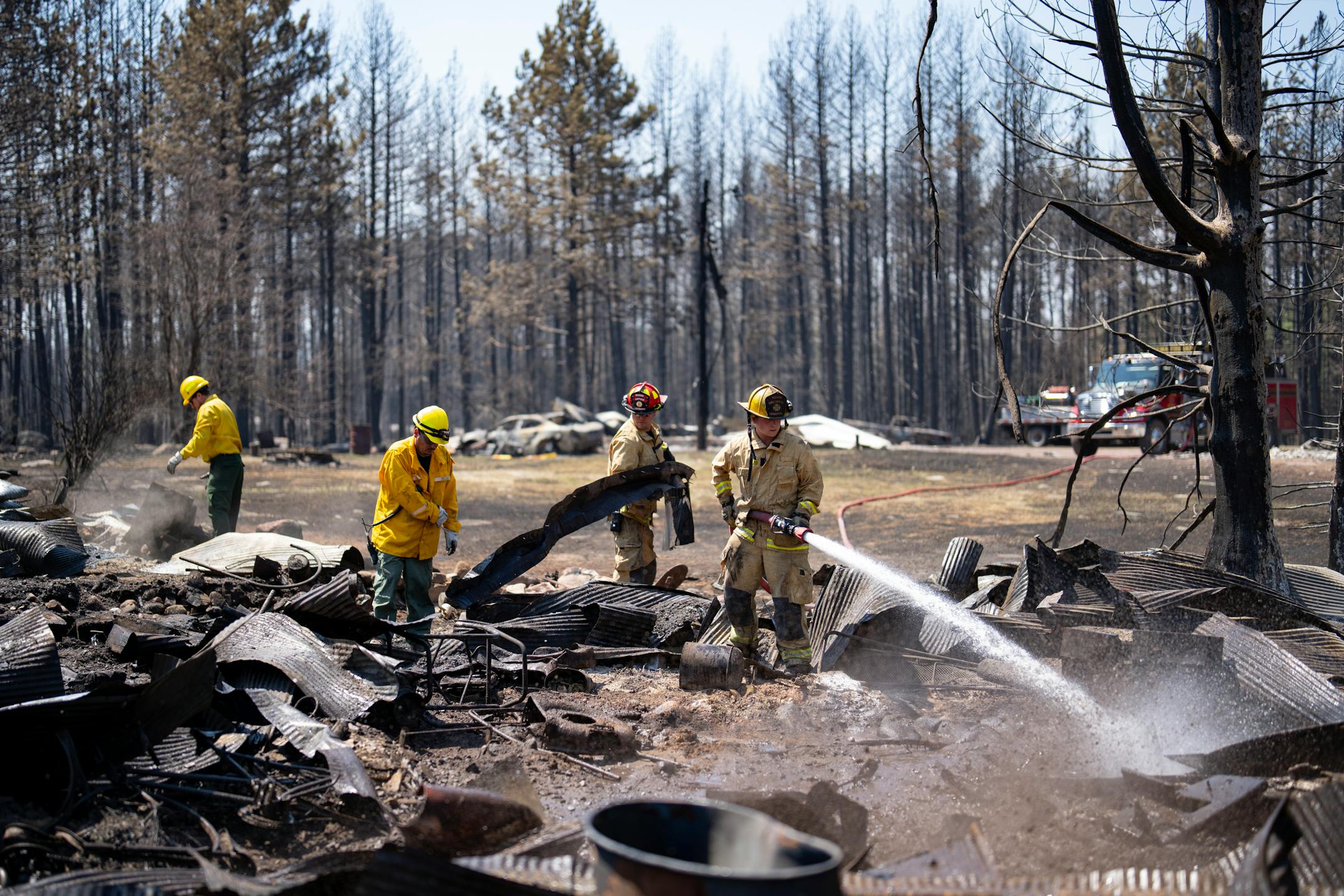 Firefighters Joshua Donahue, Chris Schlosser, Jon Settergren, Michael Hemmerich, left to right, move debris and water down hot spots in the smoldered remains of a structure as part of the efforts to combat the Camp House wildfire in Brimson, Minn. on Thursday, May 15, 2025.   ]

ALEX KORMANN • alex.kormann@startribune.com