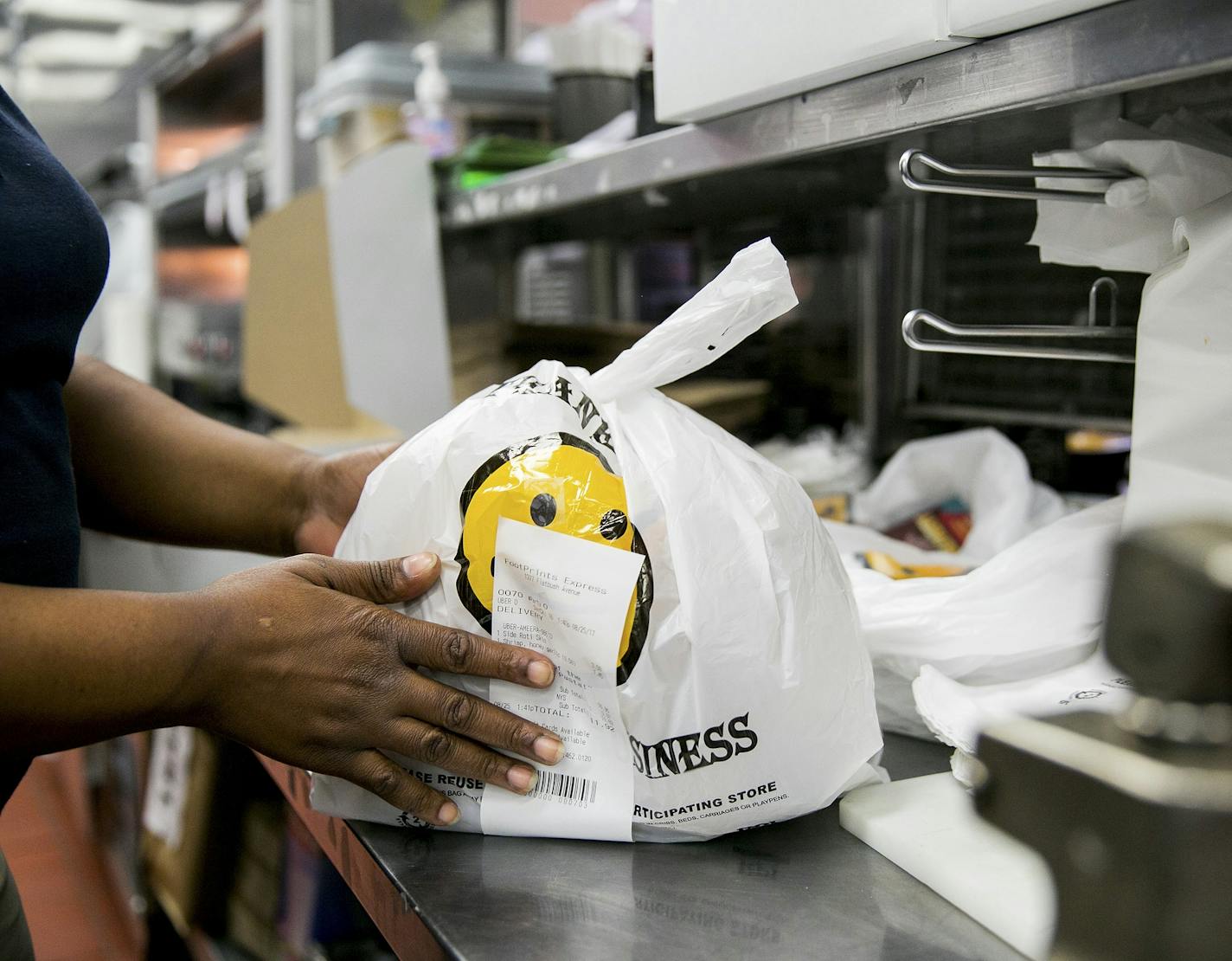 Simone Grant Creech bags orders for UberEats drivers to pick up at Footprints Cafe Express, in New York, Aug. 26, 2017. UberEats, available in more than 120 markets globally, sometimes eclipses Uber&#xed;s main ride-hailing business in markets like Tokyo; Taipei, Taiwan; and Seoul, South Korea, the company says. (Sam Hodgson/The New York Times) ORG XMIT: XNYT5