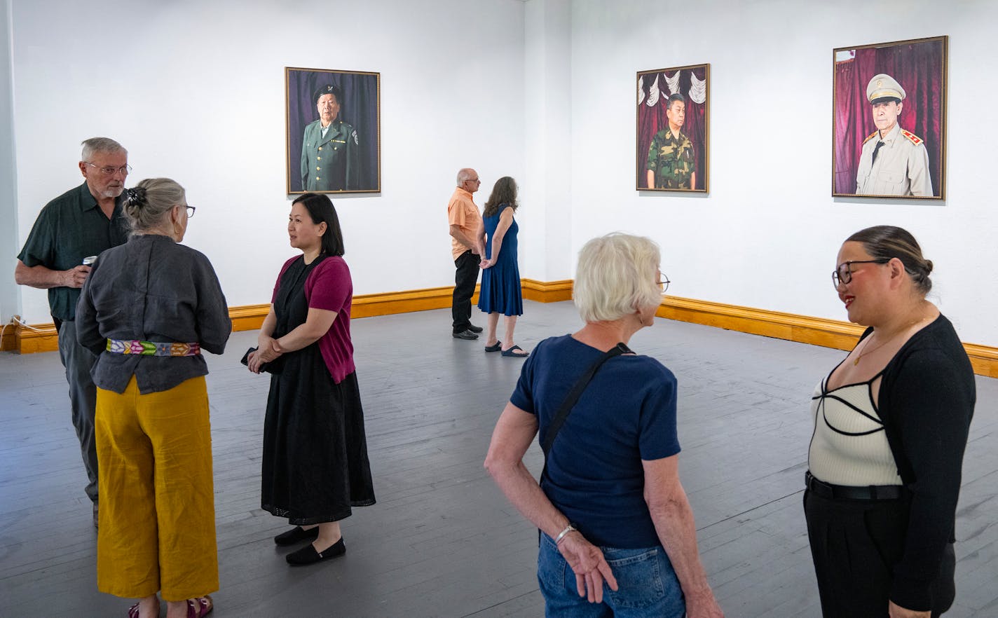 Visitors mingle and look at photgraphs by Pao Houa Her during an artist reception Friday, May 26, 2023, at Nemeth Art Center in Park Rapids, Minn. ]