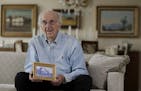 In this Friday, June 16, 2017 photo, Peter Hirschmann holds a photograph of his childhood home while posing for The Associated Press in his home in Ma