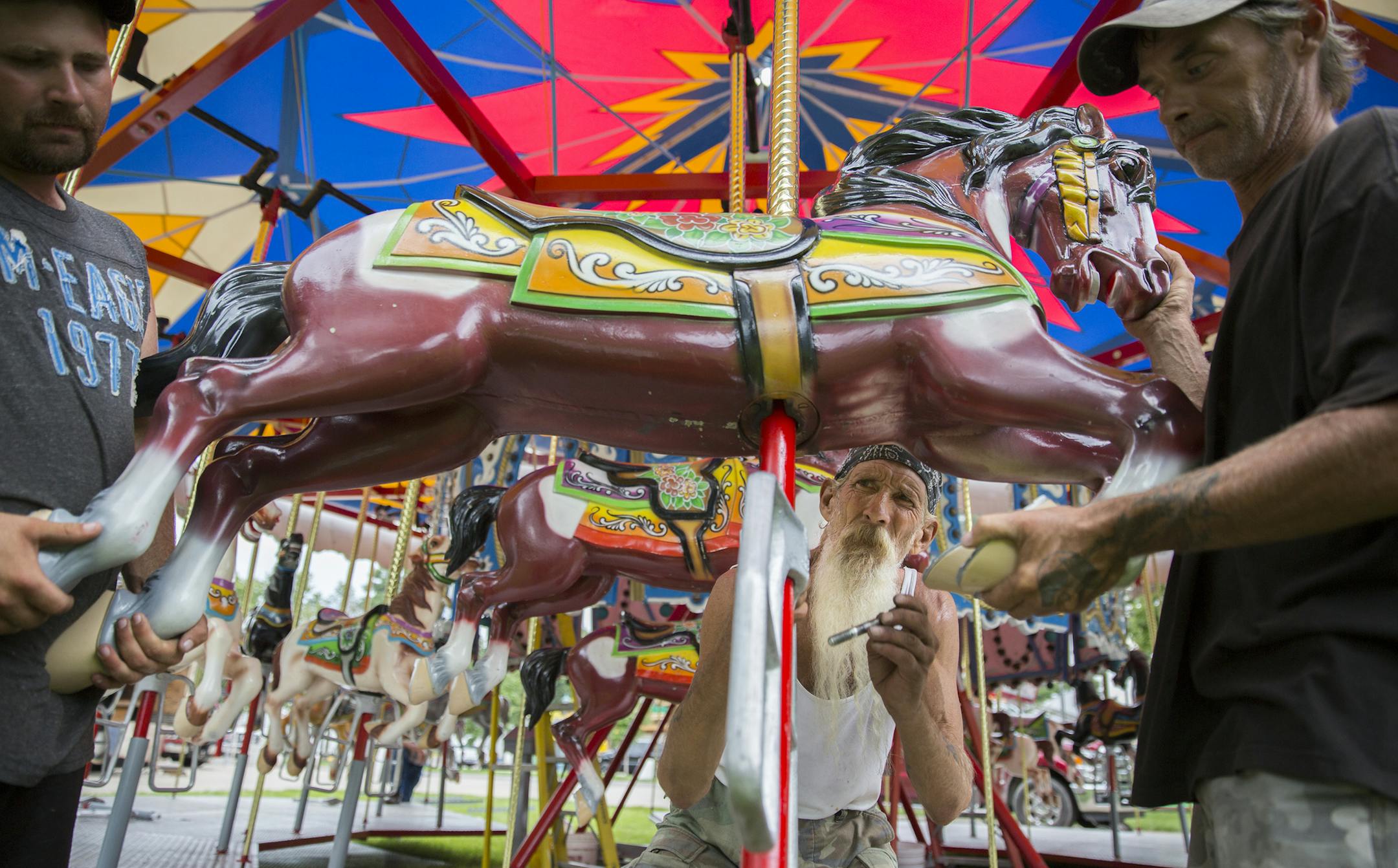 Kevin Goodin, from left, Craig "Mr. Crabs" Moore, and Michael Lindsey set up the carousel near the Grandstands at the Minnesota State Fairgrounds. ] (Leila Navidi/Star Tribune) leila.navidi@startribune.com BACKGROUND INFORMATION: Rides and booths set up the week before the Minnesota State Fair in Falcon Heights on Thursday, August 18, 2016.