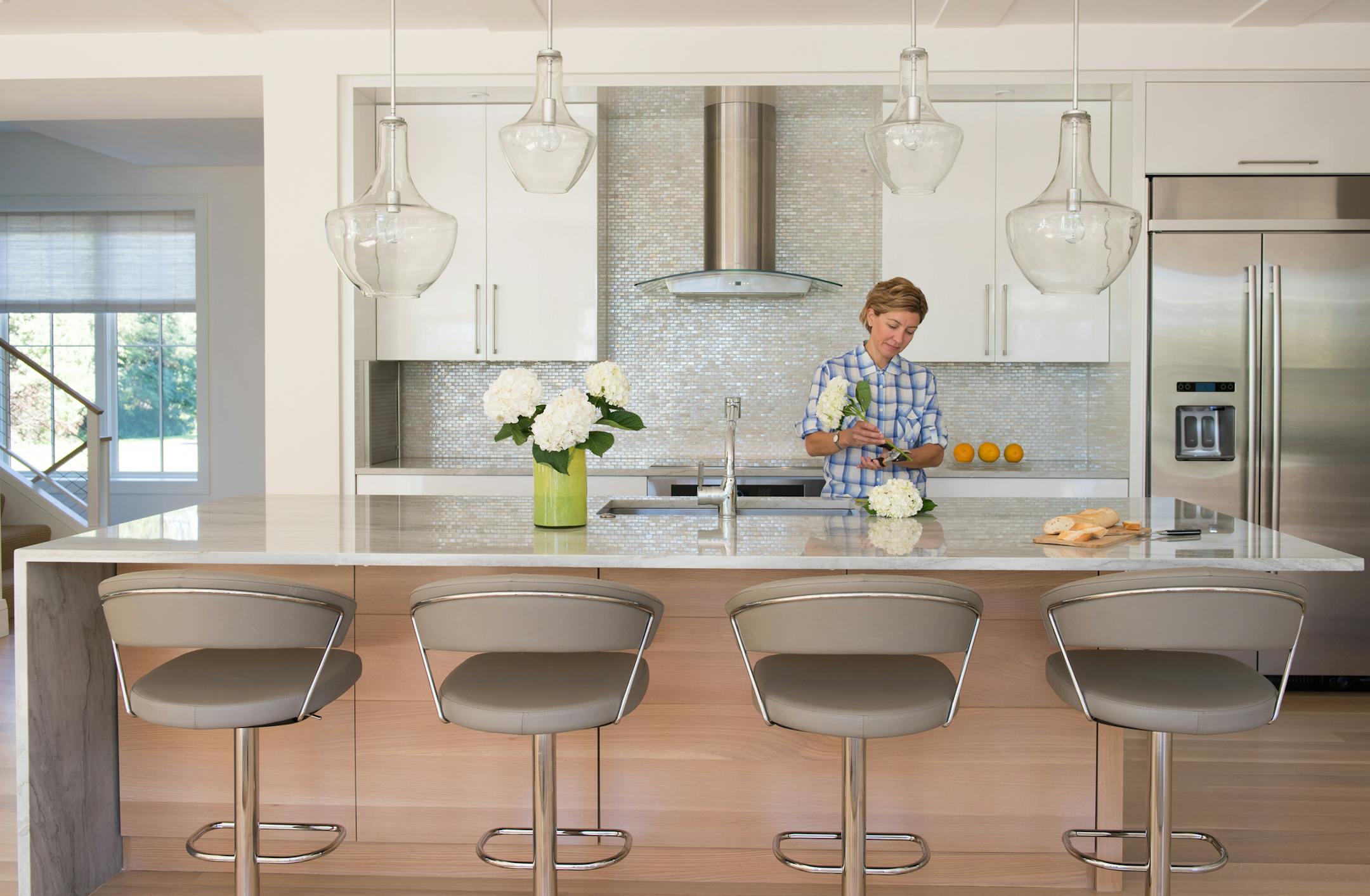 Andrea Swan can gaze at the river from her open modern kitchen featuring clear pendants etched with family names, durable laminate cabinets and iridescent glass tile backsplash.