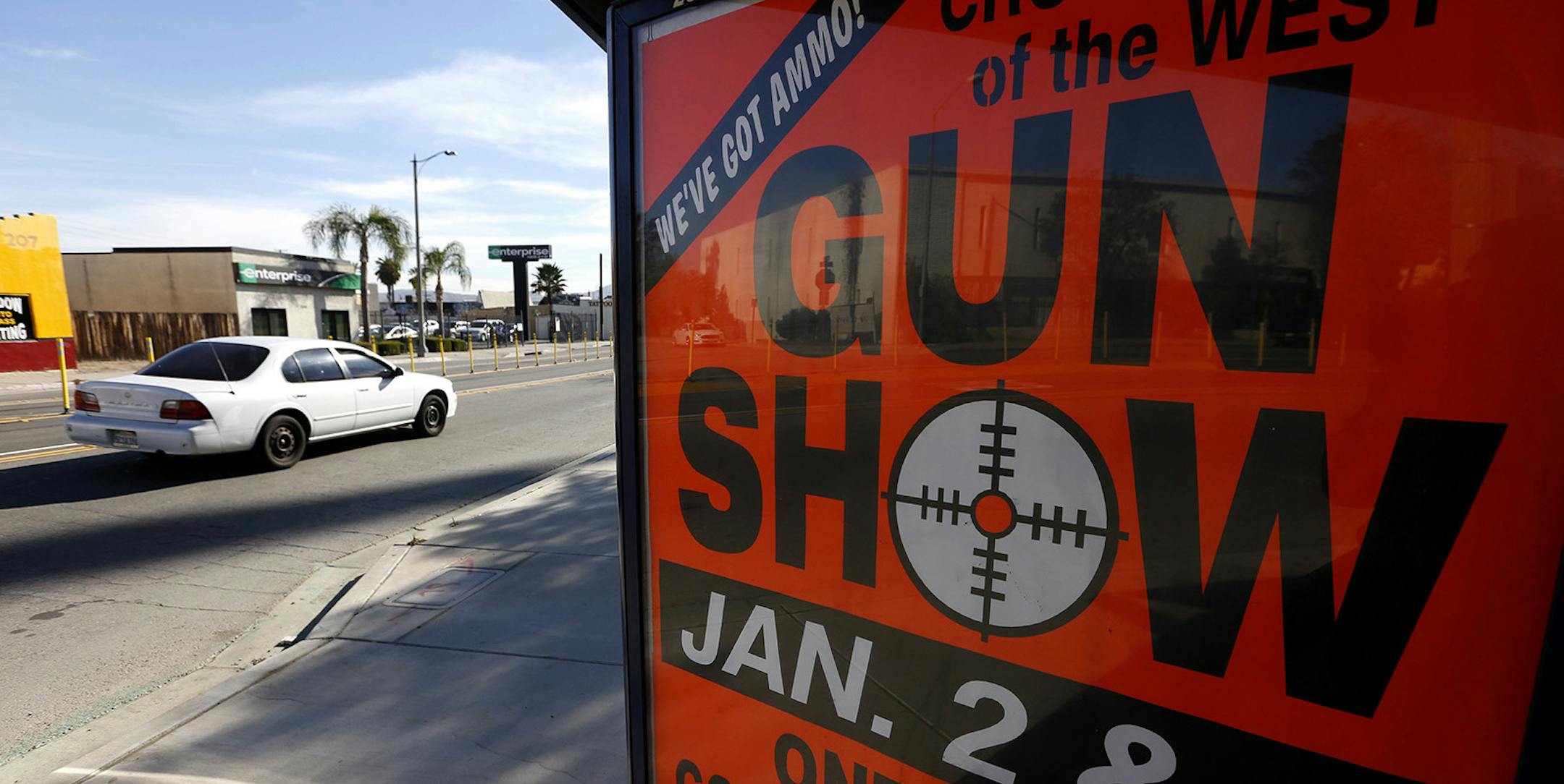 An advertisement for a gun show in Ontario is posted on a bus bench enclosure on E Street in San Bernardino on Monday, Dec. 7, 2015, just a few miles from the scene of a mass shooting that killed 14 people and injured 21 more. The sign is located in front of San Manuel Stadium, where a vigil was held for the victims. (Mark Boster/Los Angeles Times/TNS) ORG XMIT: 1388195