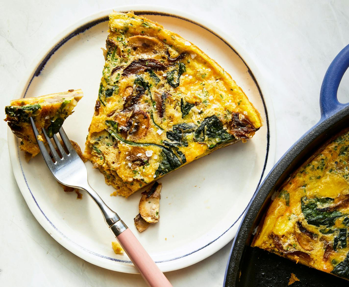 A slice of egg tart filled with herbs is cooked in a cast-iron pan.