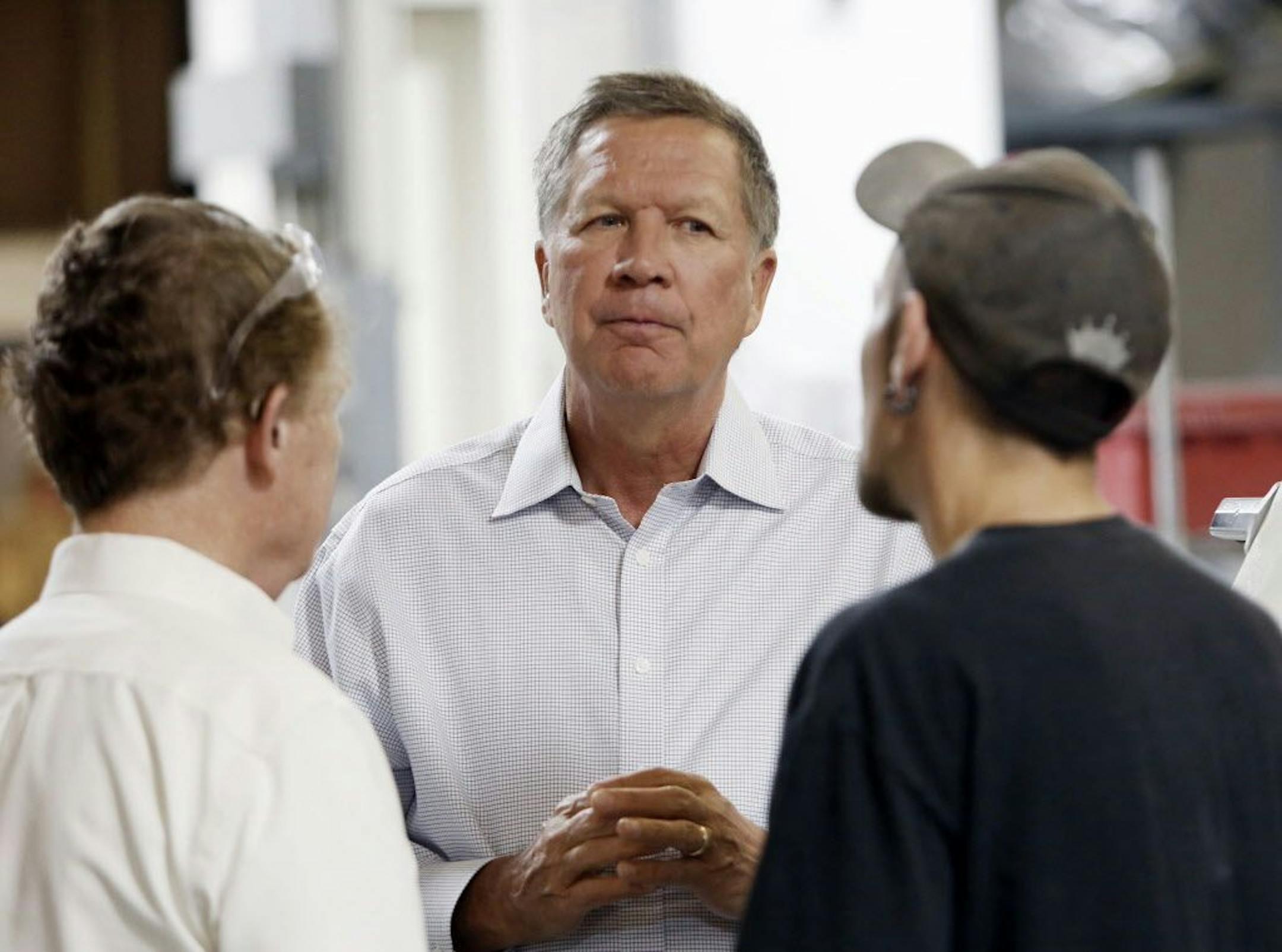 Ohio Gov. John Kasich talks with Joshua Bowman, right, and Joe Shean during a visit at RP Abrasives, Monday, July 13, 2015, in Rochester, N.H.