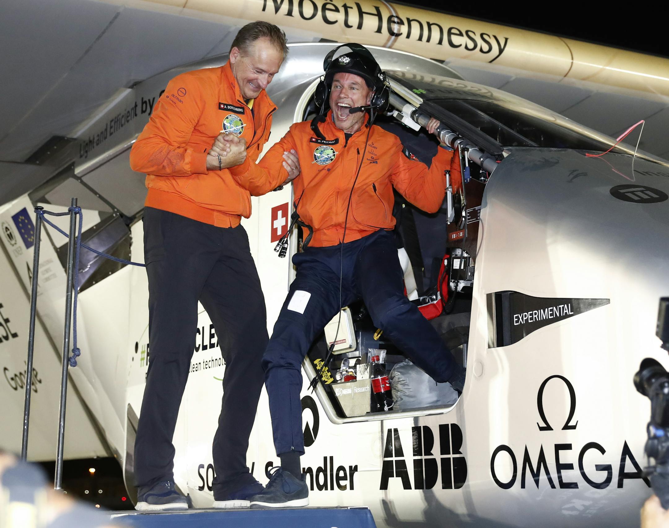 Bertrand Piccard, right, and Andre Borschberg, left, the pilots of the Solar Impulse 2 plane, celebrate in Abu Dhabi, United Arab Emirates, Tuesday, July 26, 2016. The world's first round-the-world flight to be powered solely by the sun's energy made history on Tuesday as it landed in Abu Dhabi, where it first took off on an epic 25,000-mile (40,000-kilometer) journey that began more than a year ago. (Peter Klaunzer/Keystone via AP)