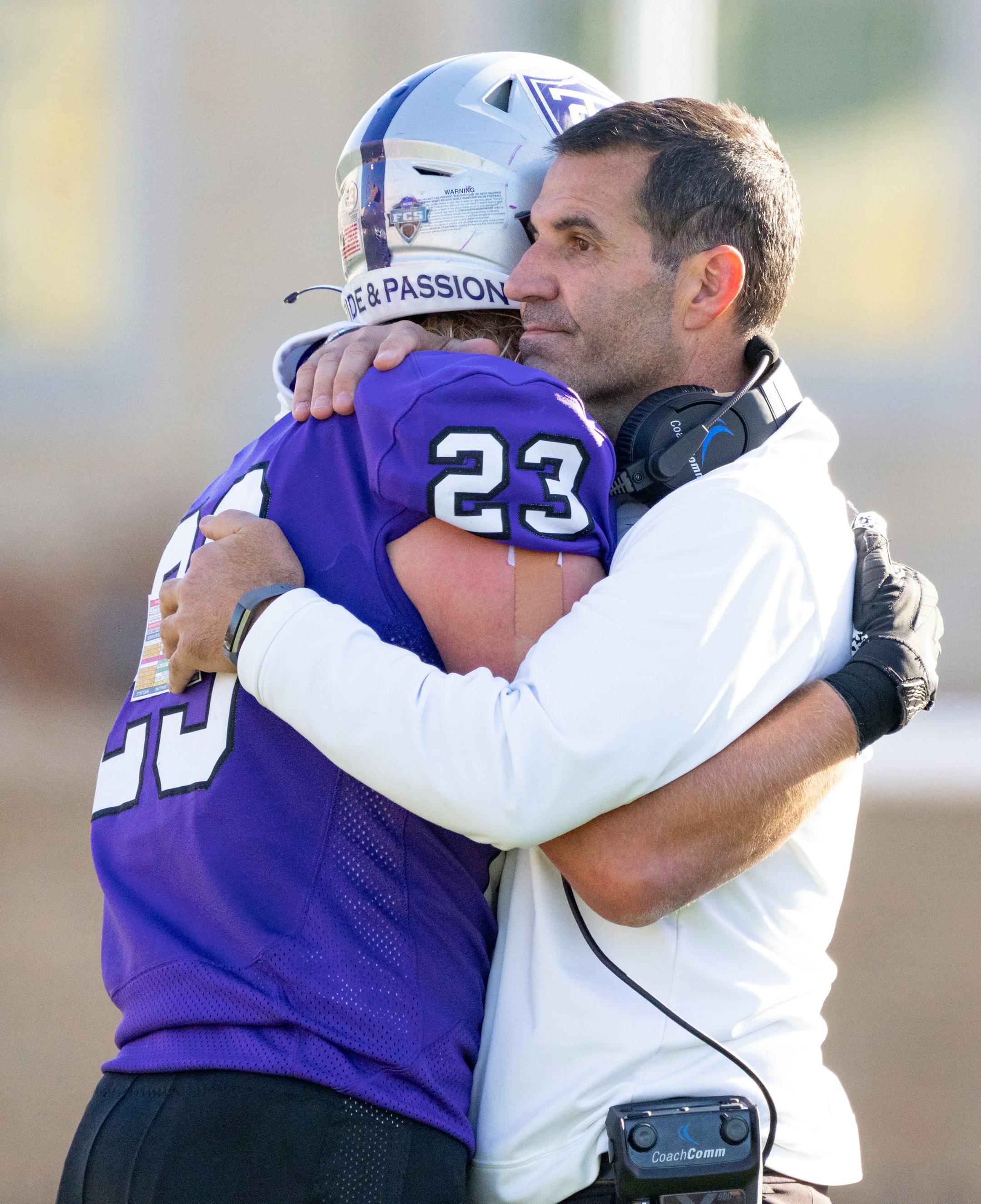 St. Thomas defensive back Luke Glenna (23) hugs head coach Glenn Caruso after forcing San Diego to turn the ball over on downs with less than ten seconds to go in the fourth quarter .