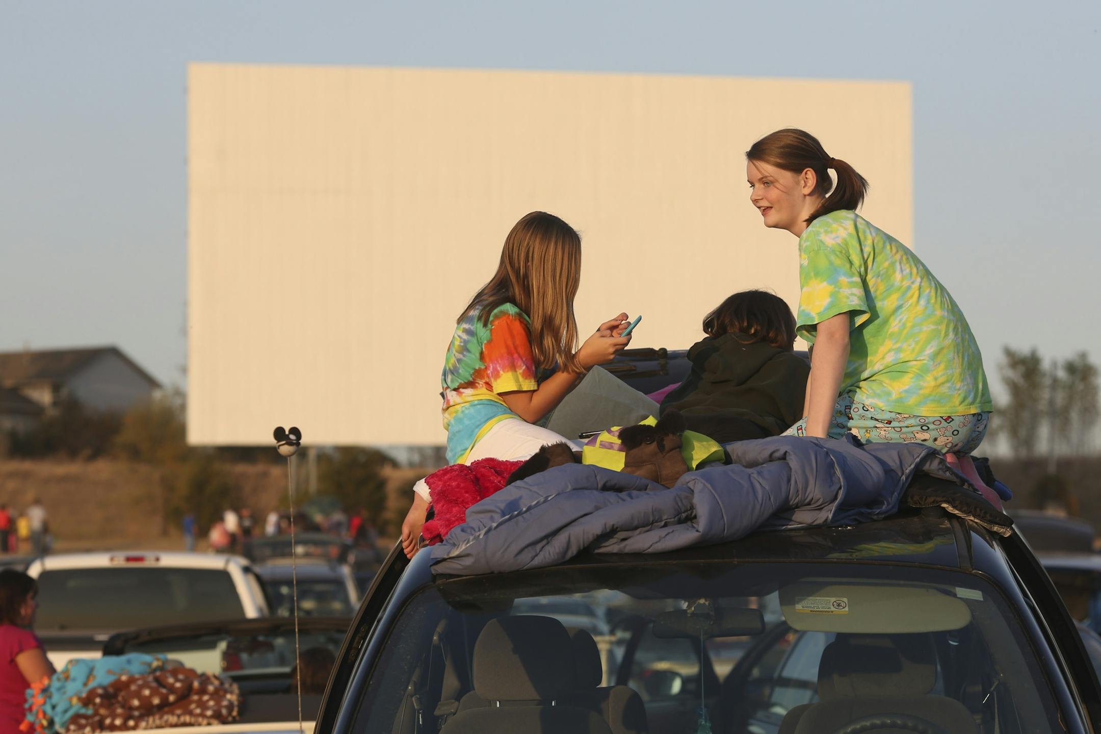 Twelve year-olds Jenna Glass, left and Ellie Schwartz, of Cottage Grove made themselves comfortable on the rooftop on a mini van during the farewell party for Cottage View Drive-In in Cottage Grove Min., Wednesday September 26, 2012. The gates had to be opened early due to the traffic along the frontage road. The first person to wait in line came at noon.