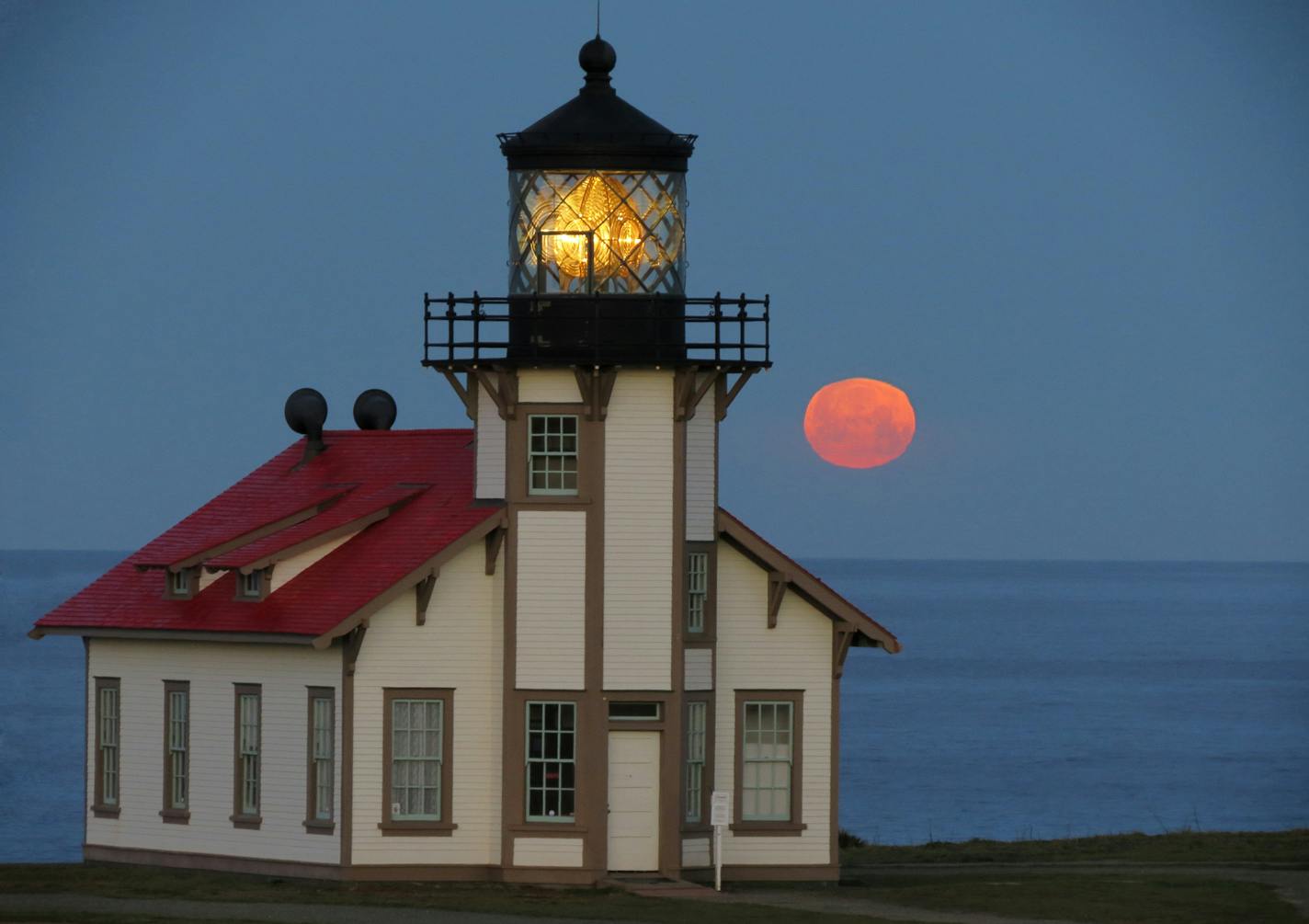 A full moon set into the Pacific beyond the Point Cabrillo Lighthouse.