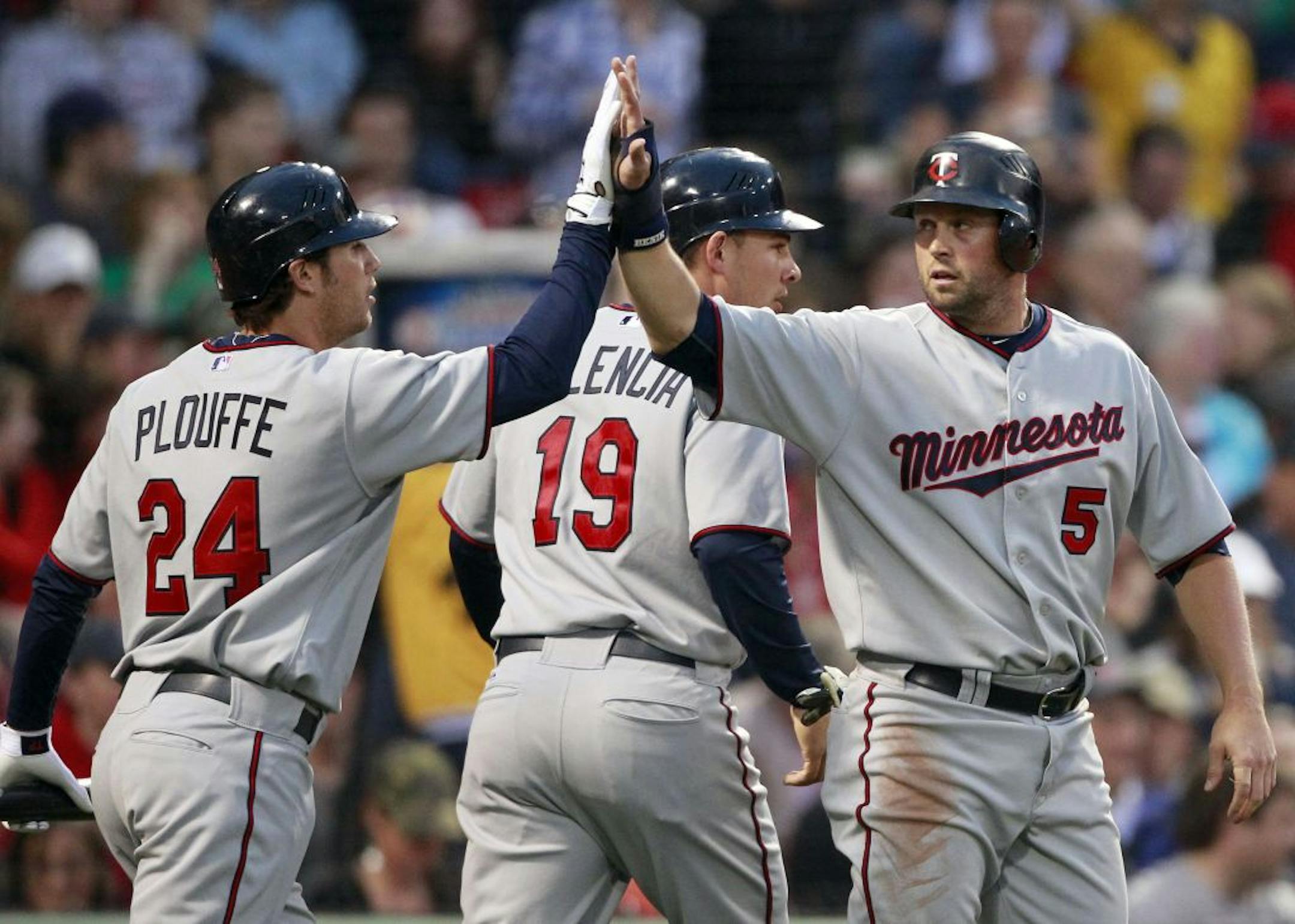 Minnesota Twins' Michael Cuddyer (5) celebrates with teammate Trevor Plouffe (24) after scoring with Danny Valencia (19) on a single by Denard Span in the second inning of a baseball game against the Boston Red Sox, Friday, May 6, 2011, in Boston.