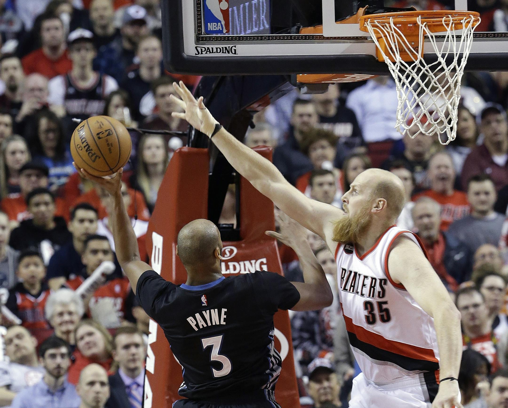 Minnesota Timberwolves forward Adreian Payne, left, shoots against Portland Trail Blazers center Chris Kaman during the first half of an NBA basketball game in Portland, Ore., Wednesday, April 8, 2015. (AP Photo/Don Ryan)
