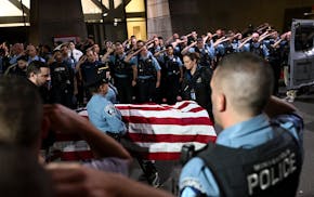Members of law enforcement stand at attention as the casket carrying the remains of a Minneapolis Police officer who was fatally shot earlier in the d