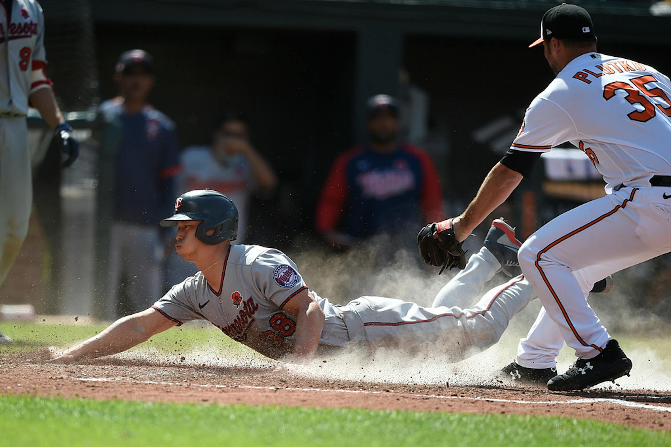 Minnesota Twins' Rob Refsnyder, left, slides across the plate as Baltimore Orioles pitcher Adam Plutko covers in the 10th inning of a baseball game Monday, May 31, 2021, in Baltimore. Refsnyder was safe, scoring the go-ahead run on a wild pitch. (AP Photo/Gail Burton)