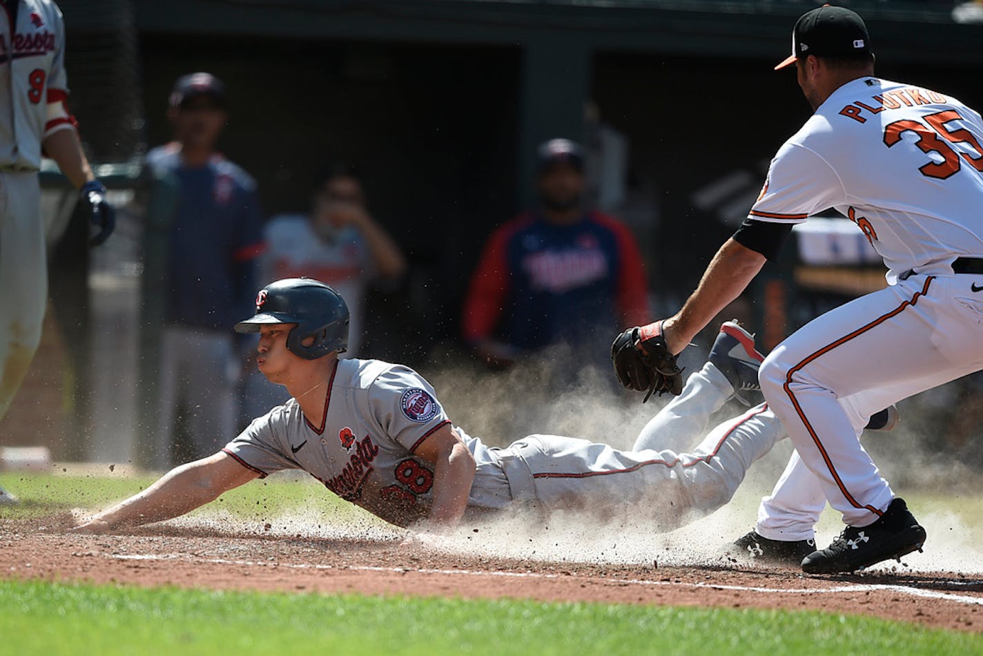 Minnesota Twins' Rob Refsnyder, left, slides across the plate as Baltimore Orioles pitcher Adam Plutko covers in the 10th inning of a baseball game Monday, May 31, 2021, in Baltimore. Refsnyder was safe, scoring the go-ahead run on a wild pitch. (AP Photo/Gail Burton)