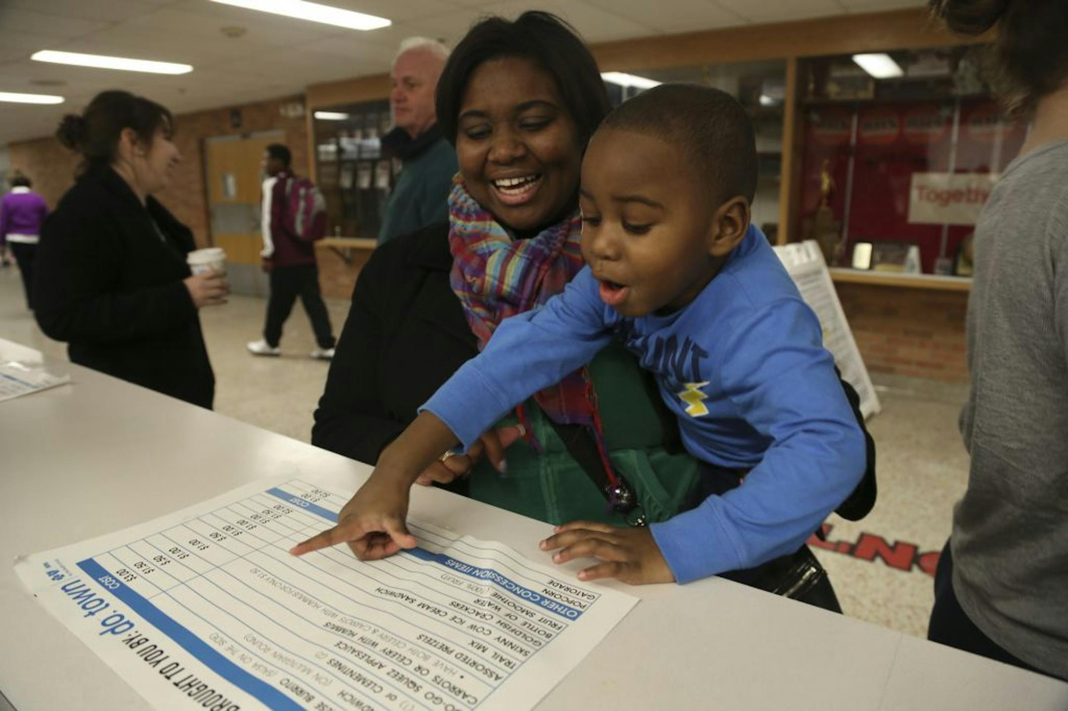 Channa Jones held her son Jeremiah Jones, 3,as he piked from the healthier fare that was available at the concession stand when Richfield Varsity basketball team played Hill Murray in Richfield, Min., Tuesday January 22, 2013.