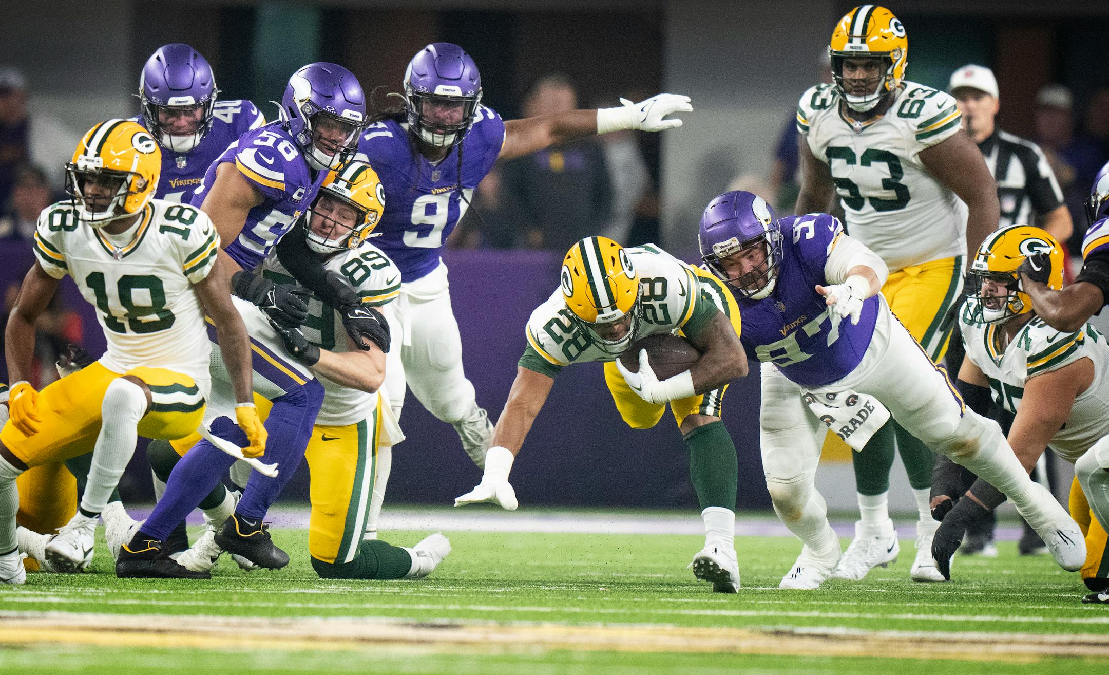 Green Bay Packers running back AJ Dillon (28) picked up a first quarter first down of 11 yards and was tackled by Minnesota Vikings defensive tackle Harrison Phillips (97) Sunday December ,31, 2023 in, Minneapolis, Minn. ] JERRY HOLT • jerry.holt@startribune.com