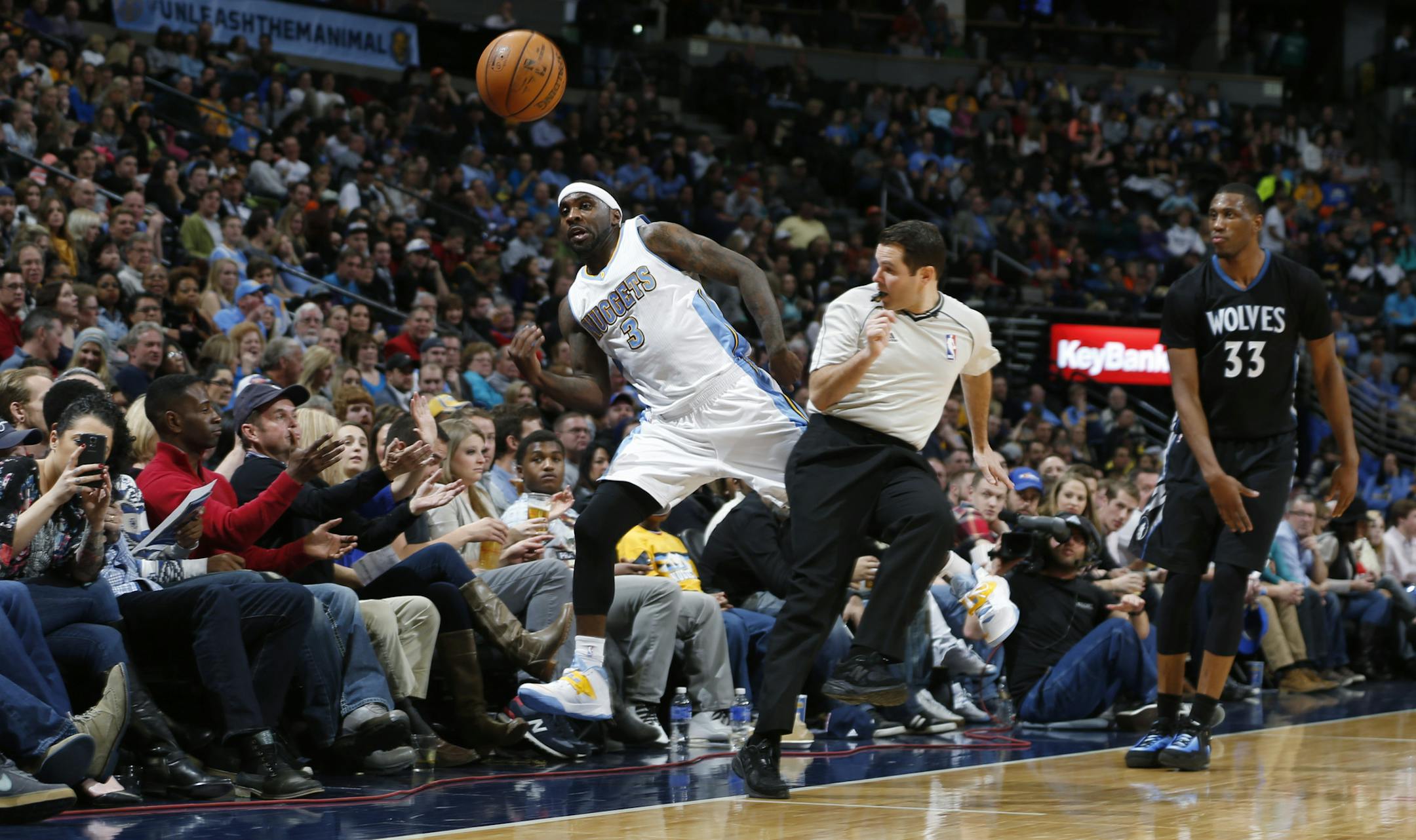 Denver Nuggets guard Ty Lawson, front left, dashes past referee Brian Forte in an effort to keep the ball in play as Minnesota Timberwolves forward Thaddeus Young watches with fans during the third quarter of an NBA basketball game Saturday, Jan. 17, 2015, in Denver. The Timberwolves won 113-105. (AP Photo/David Zalubowski)