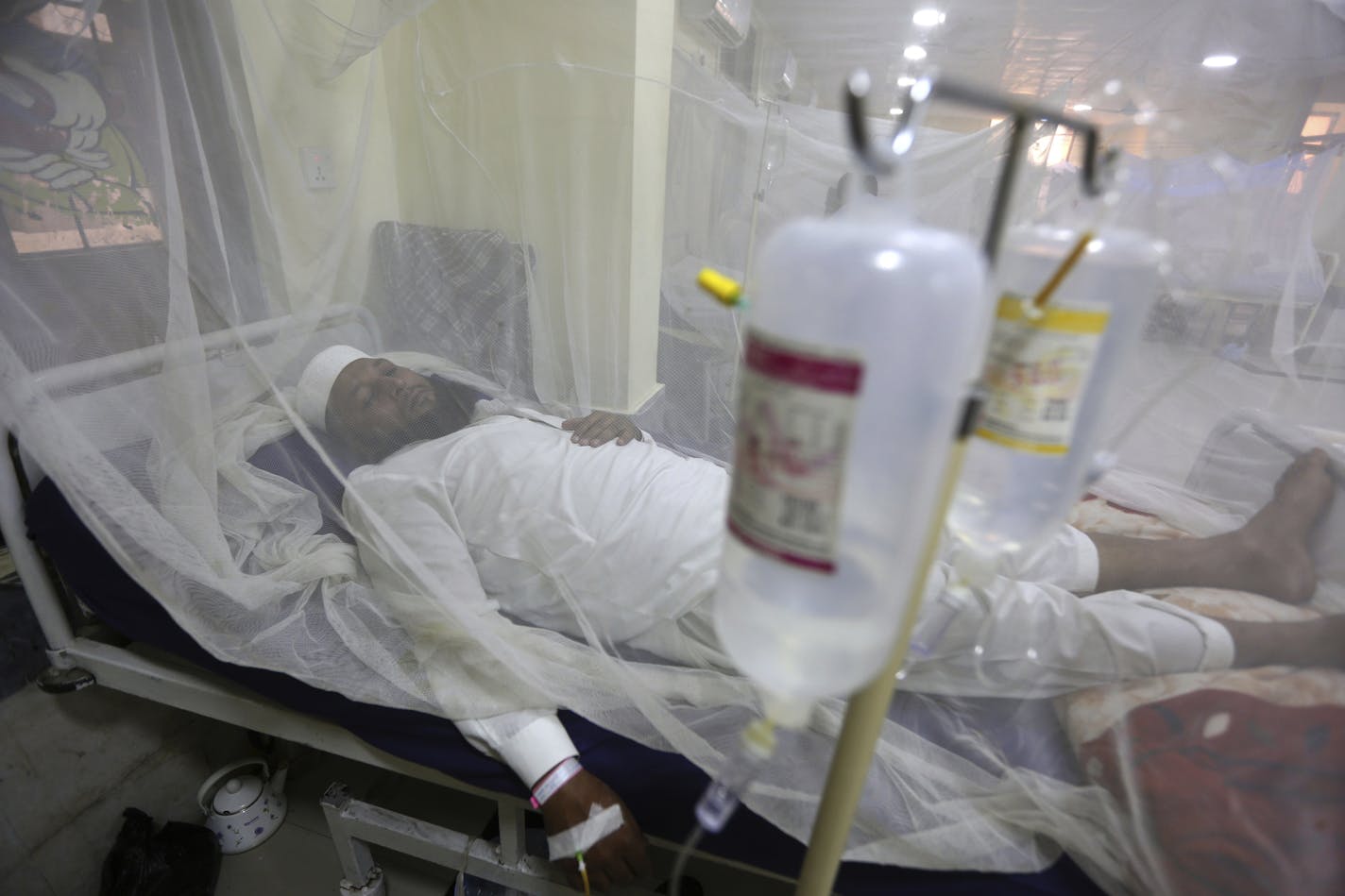 FILE - In this Thursday, Oct. 19, 2017 file photo, a patient suffering from dengue fever lies in a hospital bed in Peshawar, Pakistan. Cases of dengue fever _ a painful mosquito-borne spread disease _ have doubled every decade since 1990 with 58.4 million cases and 10,000 deaths in 2013. Dr. Howard Frumkin, a former environmental health director at the U.S. Centers for Disease Control and Prevention, said climate change, which allows mosquitoes to live in more places and stay active longer with