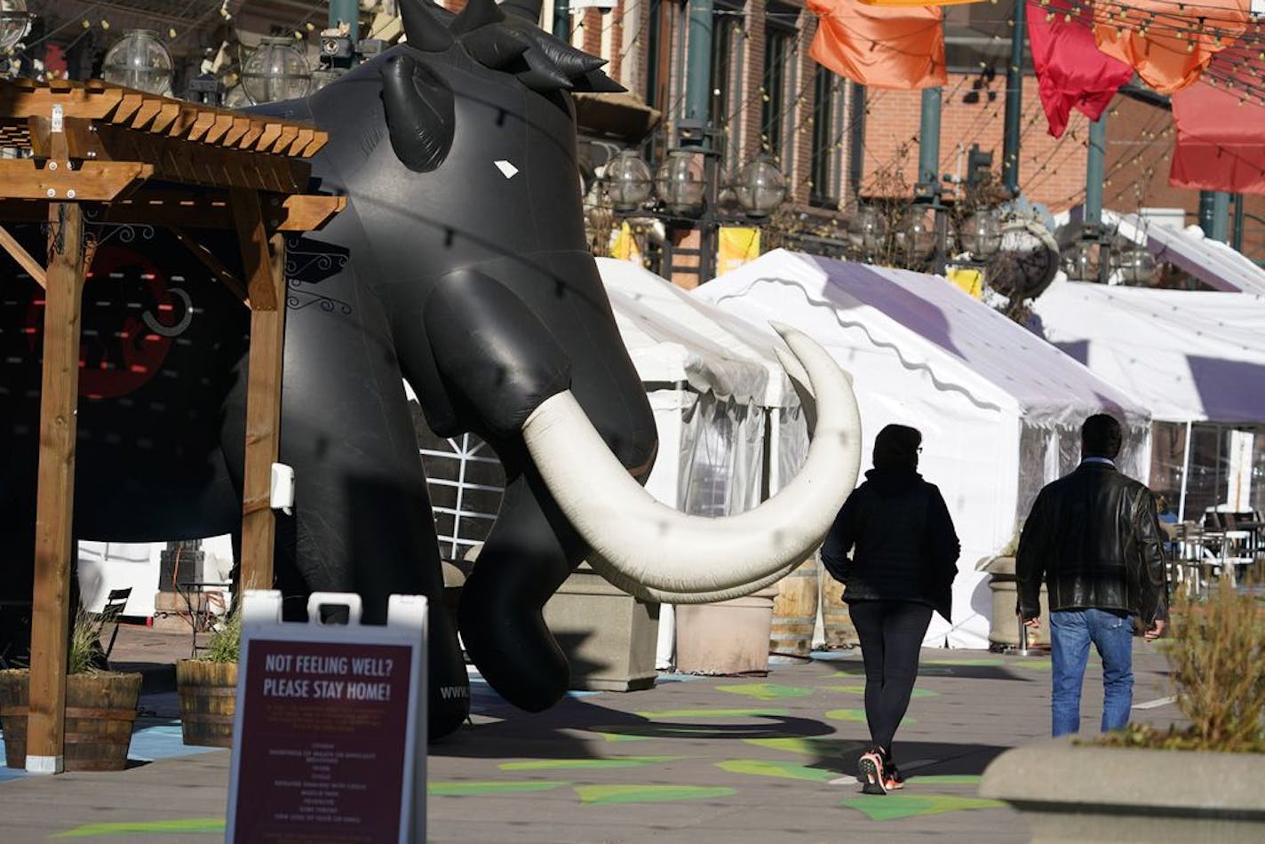 A couple passes by the row of tents put up by restaurants for outdoor dining in Larimer Square as merchants deal with the rapid spread of the coronavirus Thursday, Nov. 12, 2020, in downtown Denver. As in the rest of the nation, Colorado officials are dealing with a steep increase in the number of COVID-19 cases across the state in the past month.