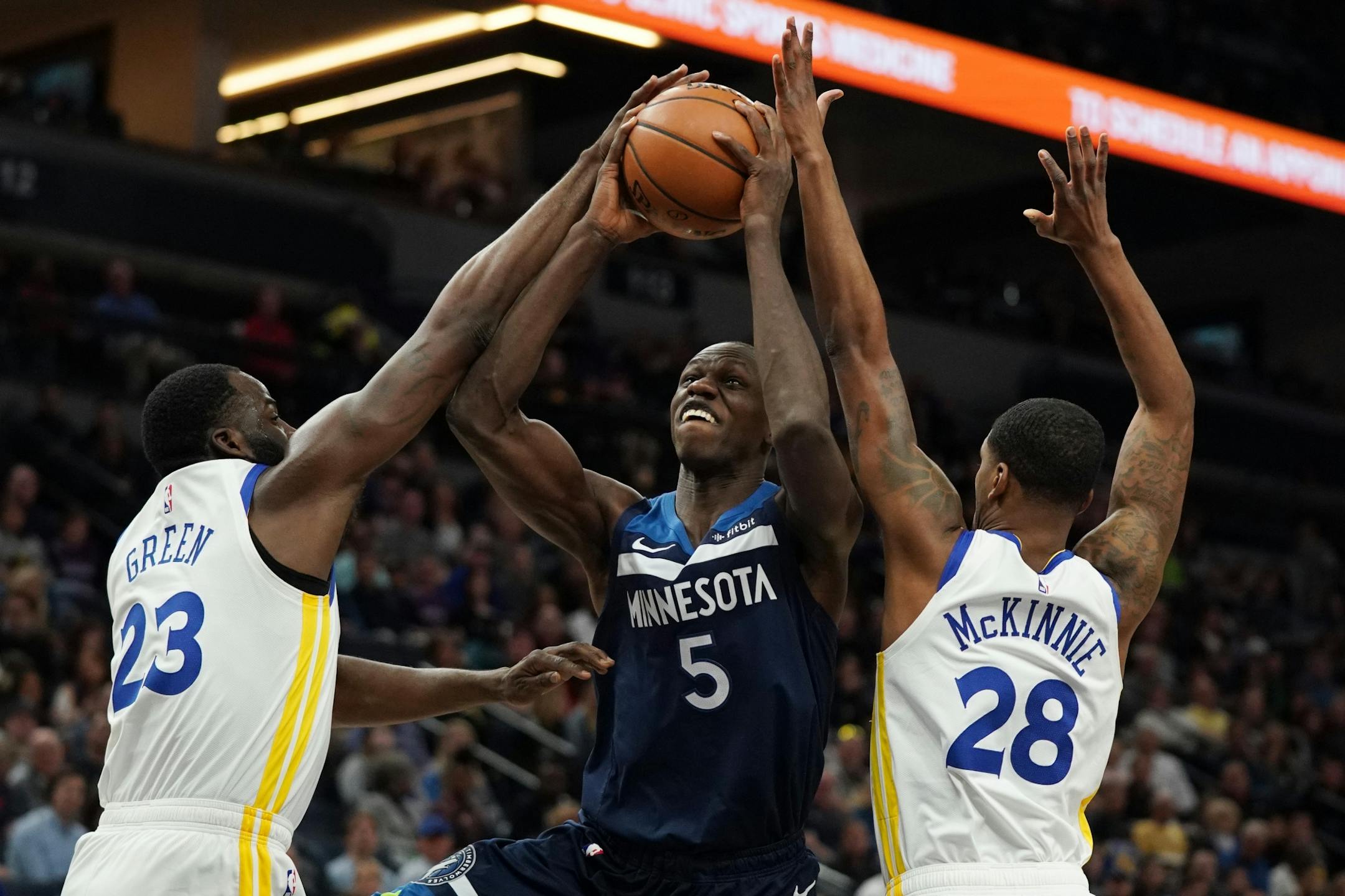 Minnesota Timberwolves center Gorgui Dieng (5) drove to the basket as Golden State Warriors forward Draymond Green (23) and Golden State Warriors forward Alfonzo McKinnie (28) defended in the first half.