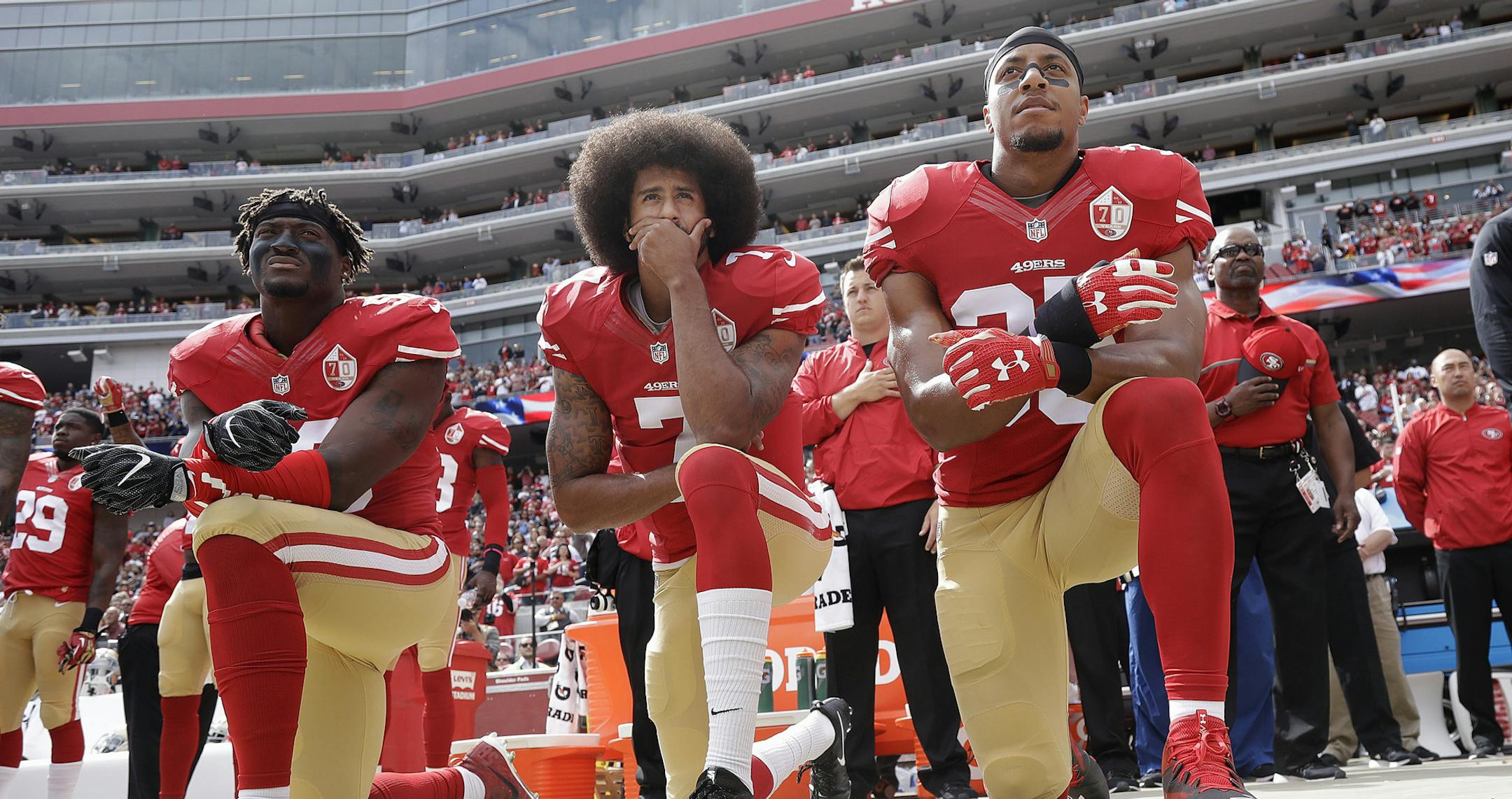 FILE - In this Oct. 2, 2016 file photo, from left, San Francisco 49ers outside linebacker Eli Harold, quarterback Colin Kaepernick and safety Eric Reid kneel during the national anthem before an NFL football game against the Dallas Cowboys in Santa Clara, Calif. An arbitrator is sending Kaepernick's grievance with the NFL to trial, denying the league's request to throw out the quarterback's claims that owners conspired to keep him out of the league because of his protests of social injustice. (A