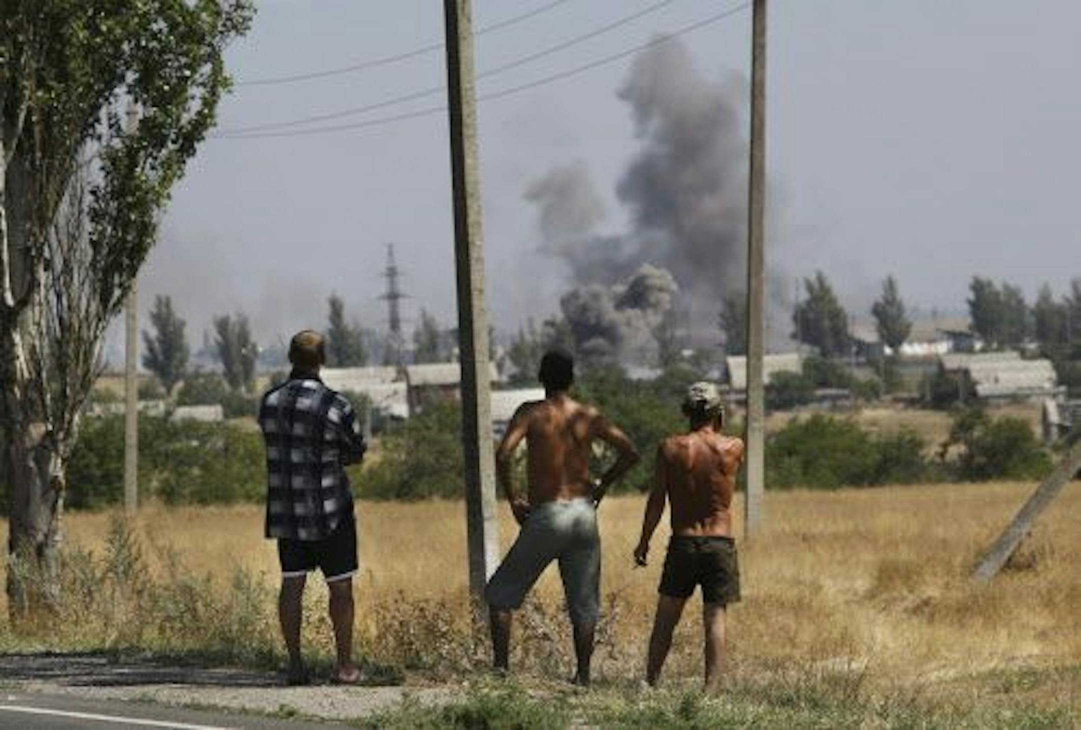 Local residents watch as smoke rises, during shelling, in the town of Novoazovsk, eastern Ukraine, Wednesday, Aug. 27, 2014.