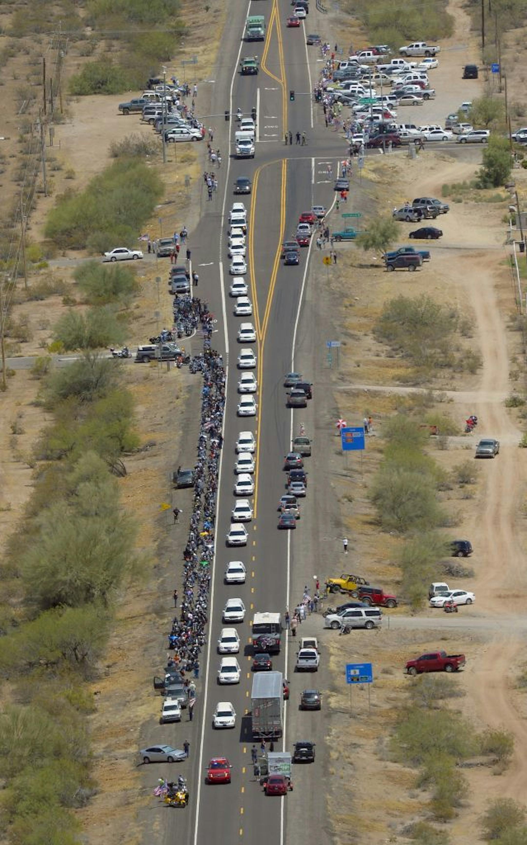A procession of 19 hearses for the 19 fallen Arizona firefighters drives through the desert, Sunday, July 7, 2013, near Wickenburg, Ariz, The elite crew of firefighters were overtaken by the out-of-control blaze as they tried to protect themselves from the flames under fire-resistant shields last Sunday.