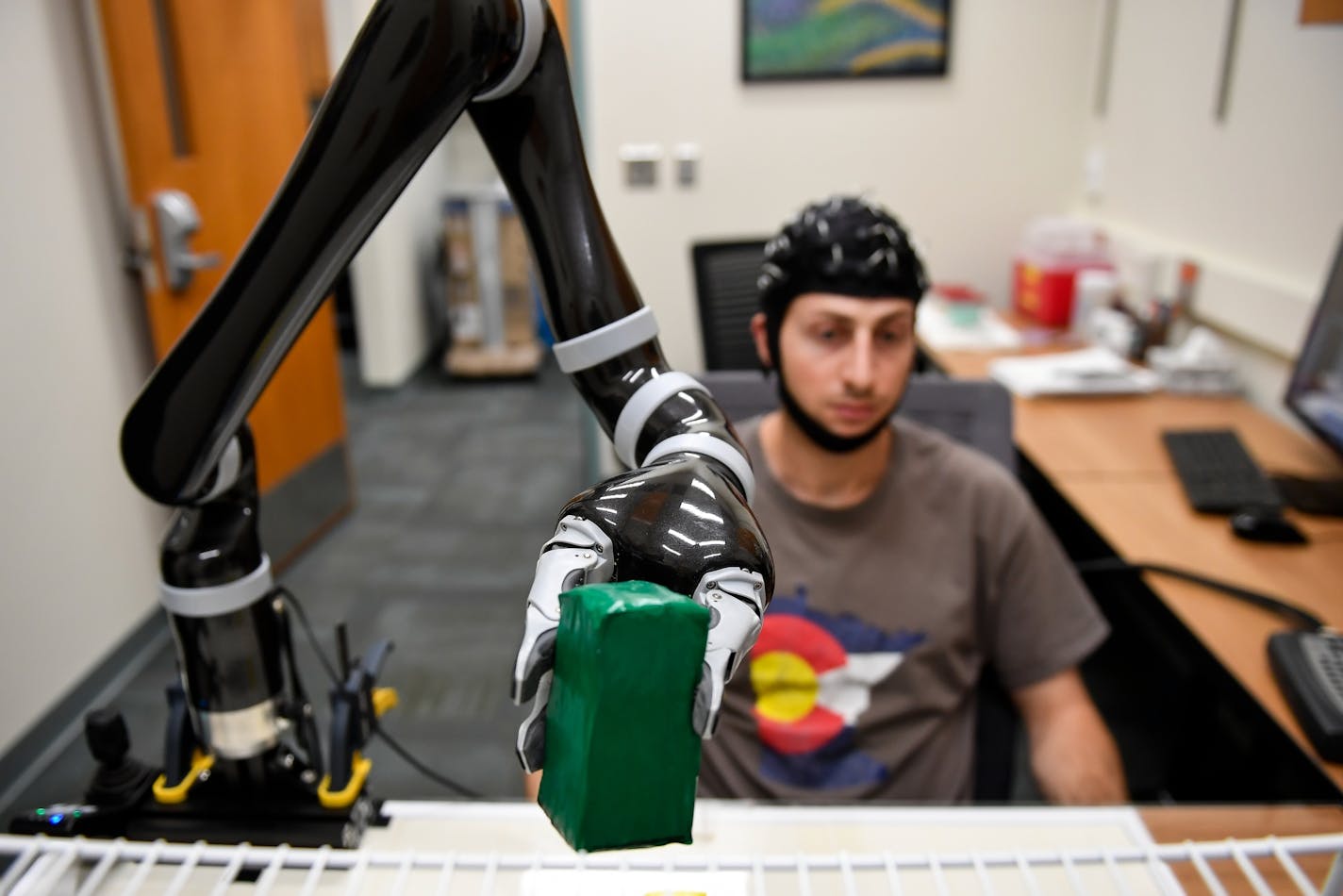 Brad Edelman, a U of M biomedical engineering graduate student, performed the basic task of moving blocks using a mind-controlled robot through an EEG cap attached to his head.