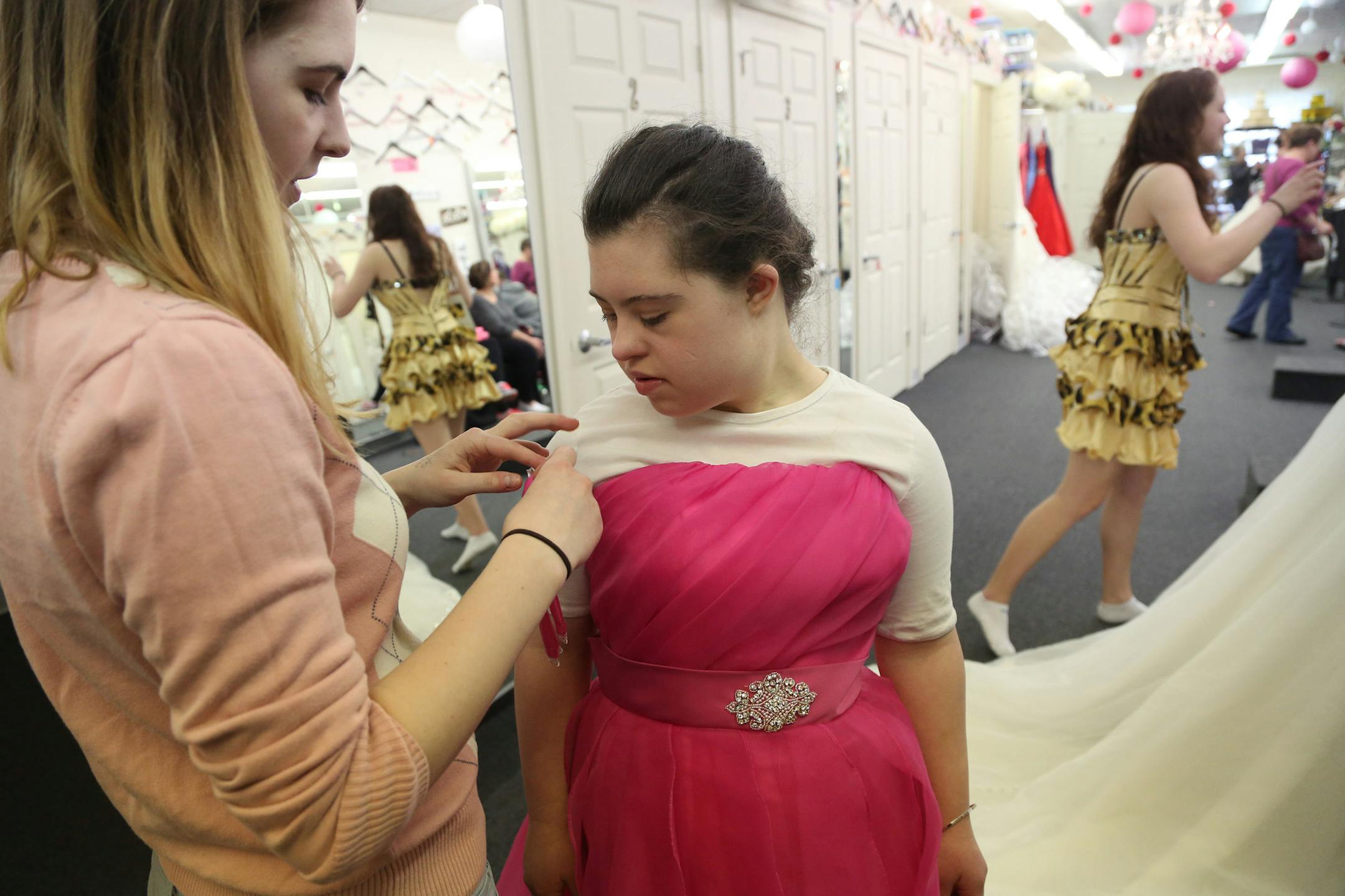 Olivia Elder, 19, got help with the straps from her older sister Nina as they looked for a formal dress for the pageant. ] (KYNDELL HARKNESS/STAR TRIBUNE) kyndell.harkness@startribune.com Nina is taking younger sister Olivia shopping for the evening gown that she will wear during the Minnesota Miss Amazing Pageant at Bride to be Consignment in Bloomington Min., Tuesday, April 7, 2014.