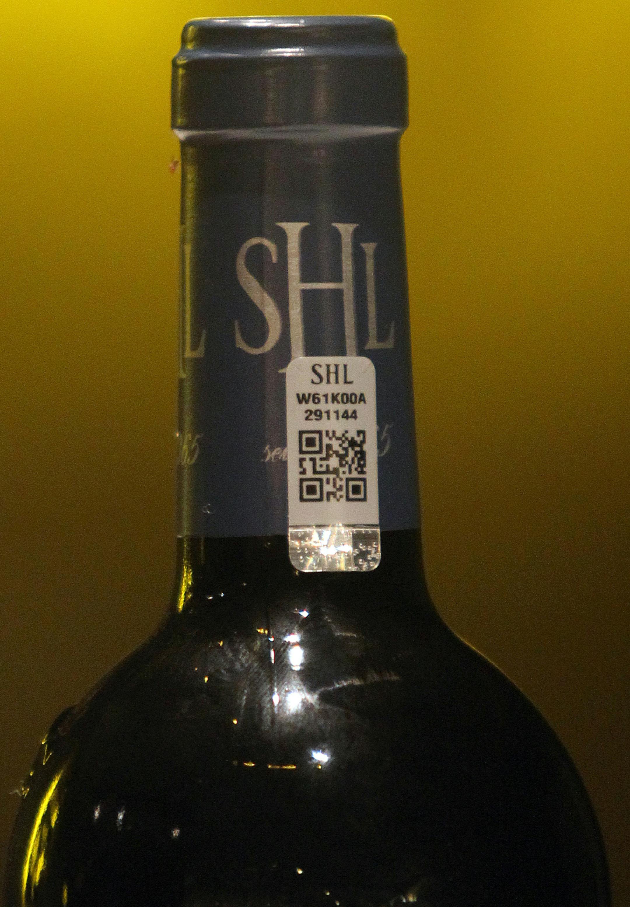 In this photo dated Wednesday, Nov. 13, 2013, an anti-fraud label is stick on a bottle of red wine Chateau Smith Haut Lafitte in Martillac, near Bordeaux, southwestern France. Counterfeiting has dogged wine as long as it has been produced, but it is getting more sophisticated and more ambitious, particularly as bottle prices rise due to huge demand in new markets, mainly in Asia. (AP Photo/Bob Edme)