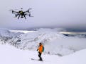 This Dec. 2014 photo shows a drone hovering by a skier as he makes his way down mountainside at resort at Revelstoke, B.C., Canada. Some US ski resort